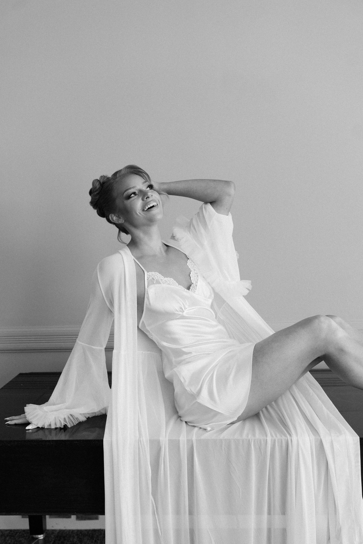 A series of black and white photos showing a figure in flowing white fabric draped across a surface in artistic poses.