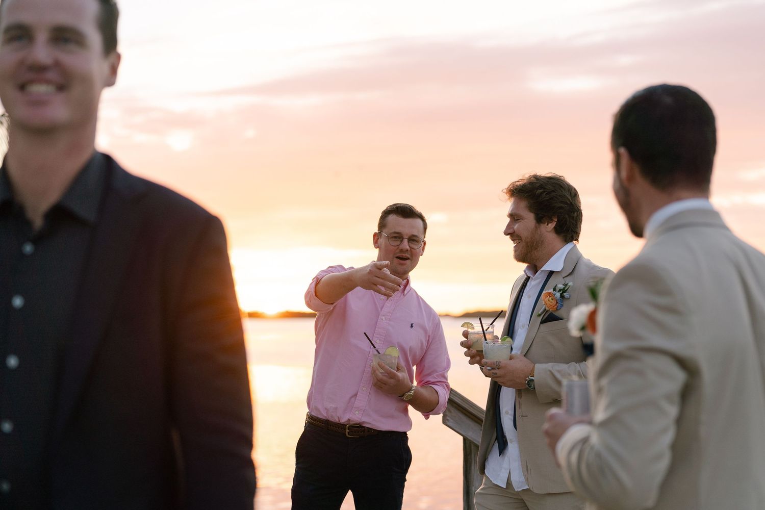 A casual outdoor gathering of friends chatting during sunset by the water.