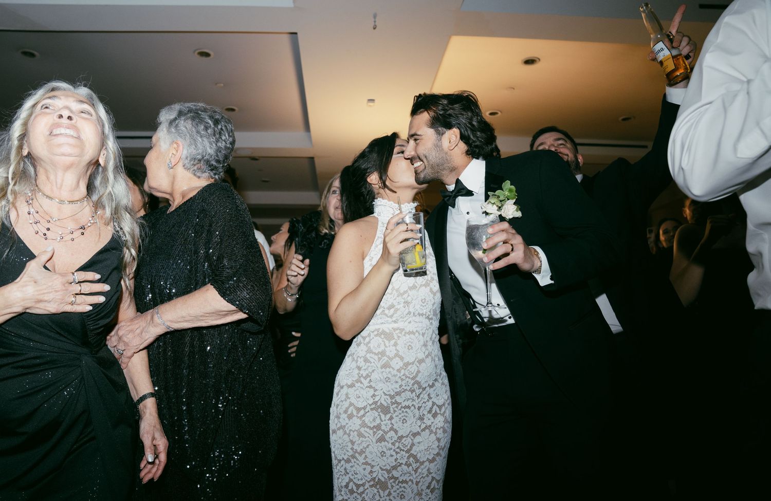 A group of people dancing and celebrating at what appears to be a wedding reception or party.