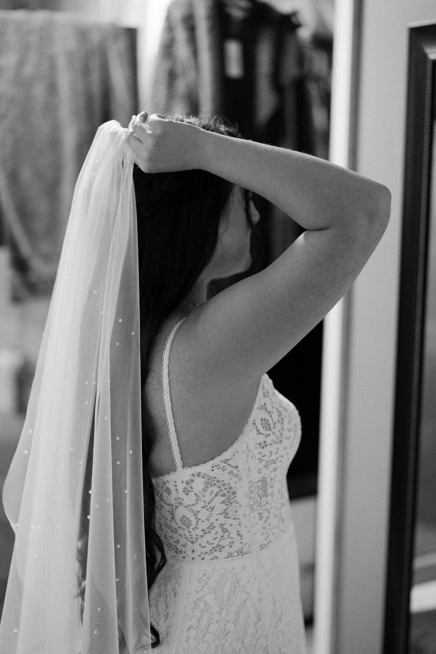 Close-up black and white detail of a wedding dress with delicate lace and flowing veil.