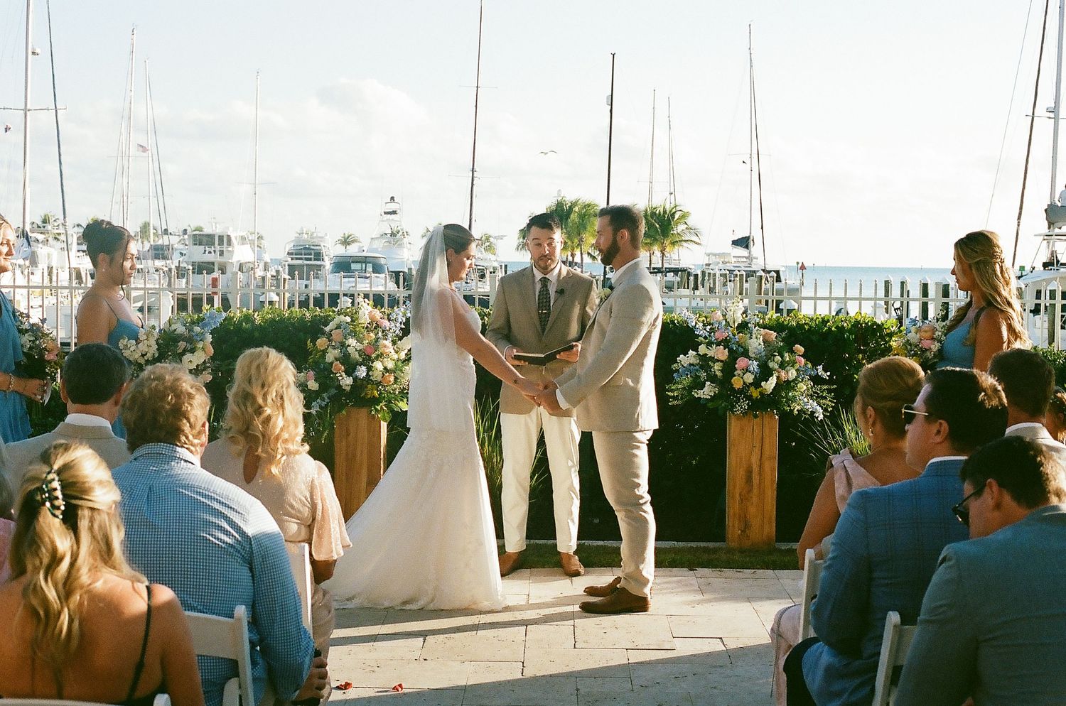 A rooftop wedding ceremony overlooking a coastal town with boats and blue water in the background.