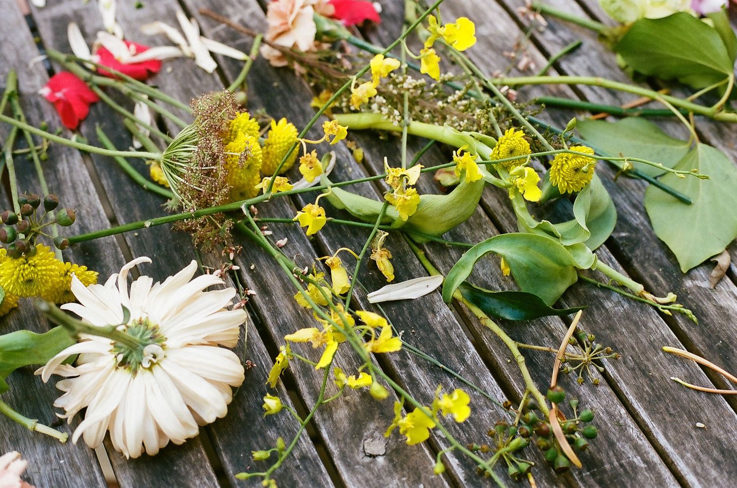 Colorful flowers including red, yellow and white blooms arranged on weathered wooden planks.