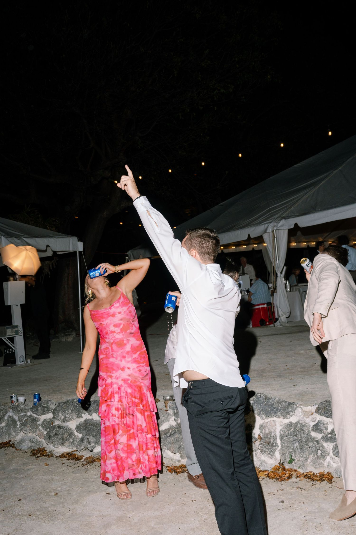 People are dancing and celebrating at an outdoor event under a starry night sky.