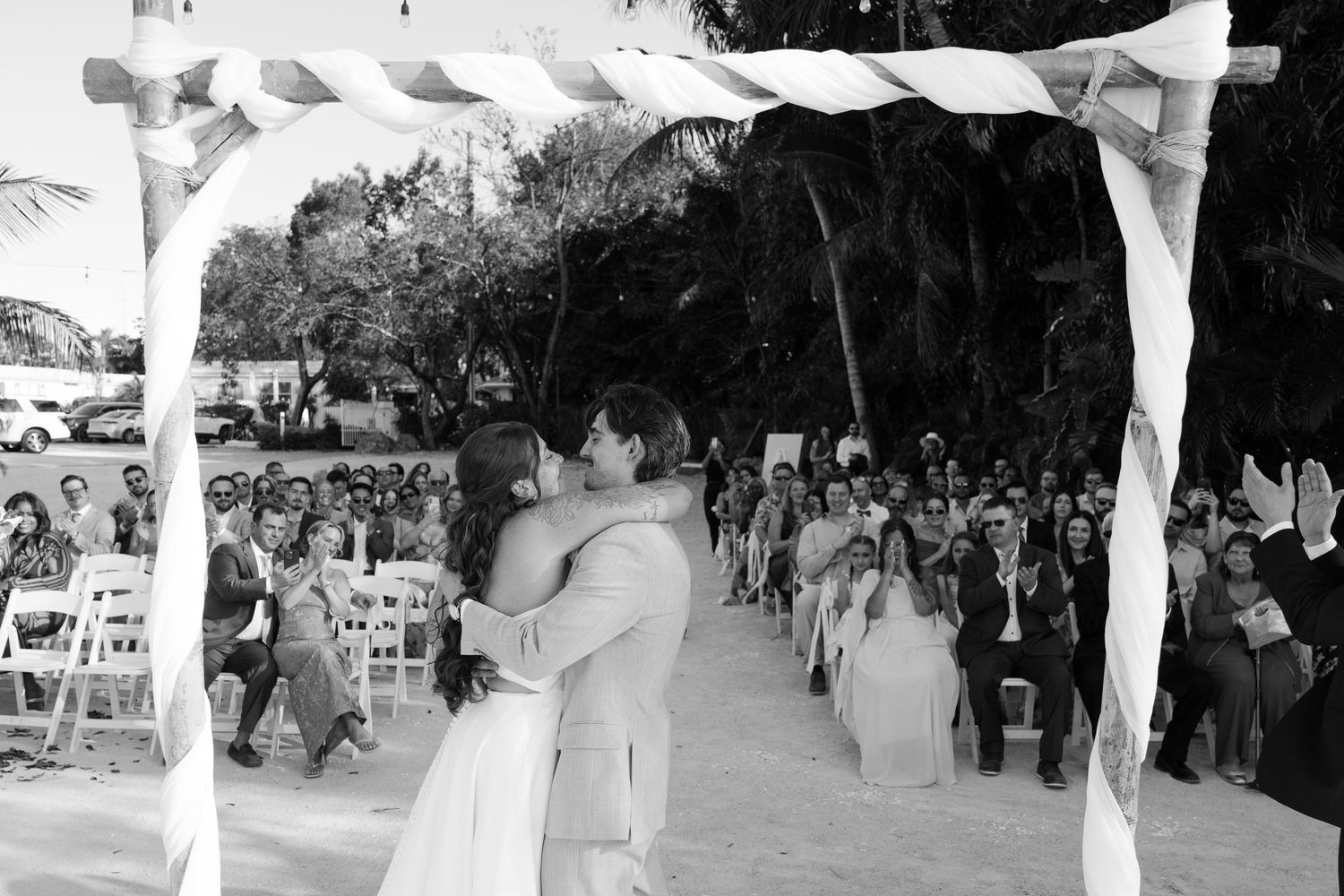 A black and white image of a couple dancing at a wedding reception under a decorated archway.