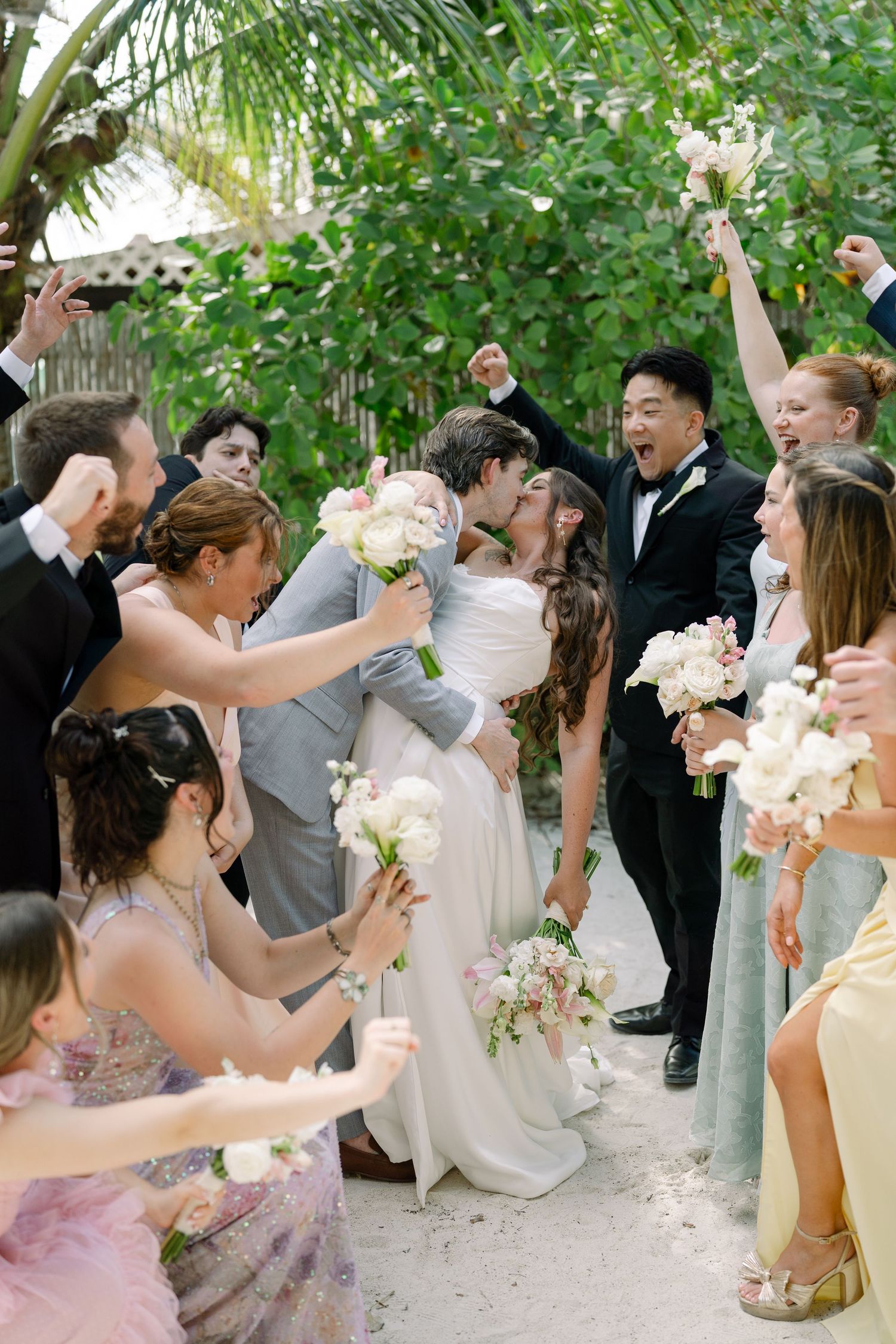 A wedding party celebrates the newlyweds in a lush tropical setting.