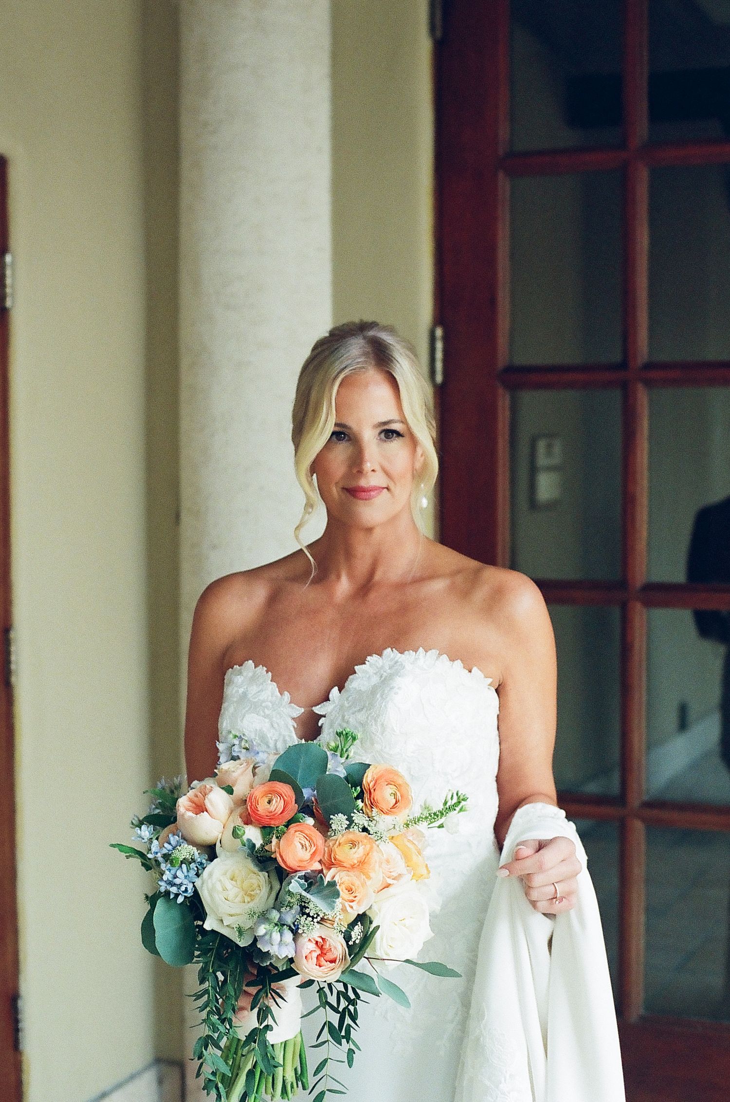 Elegant bridal portraits showing white wedding dress and peach and white floral bouquet against neutral background.