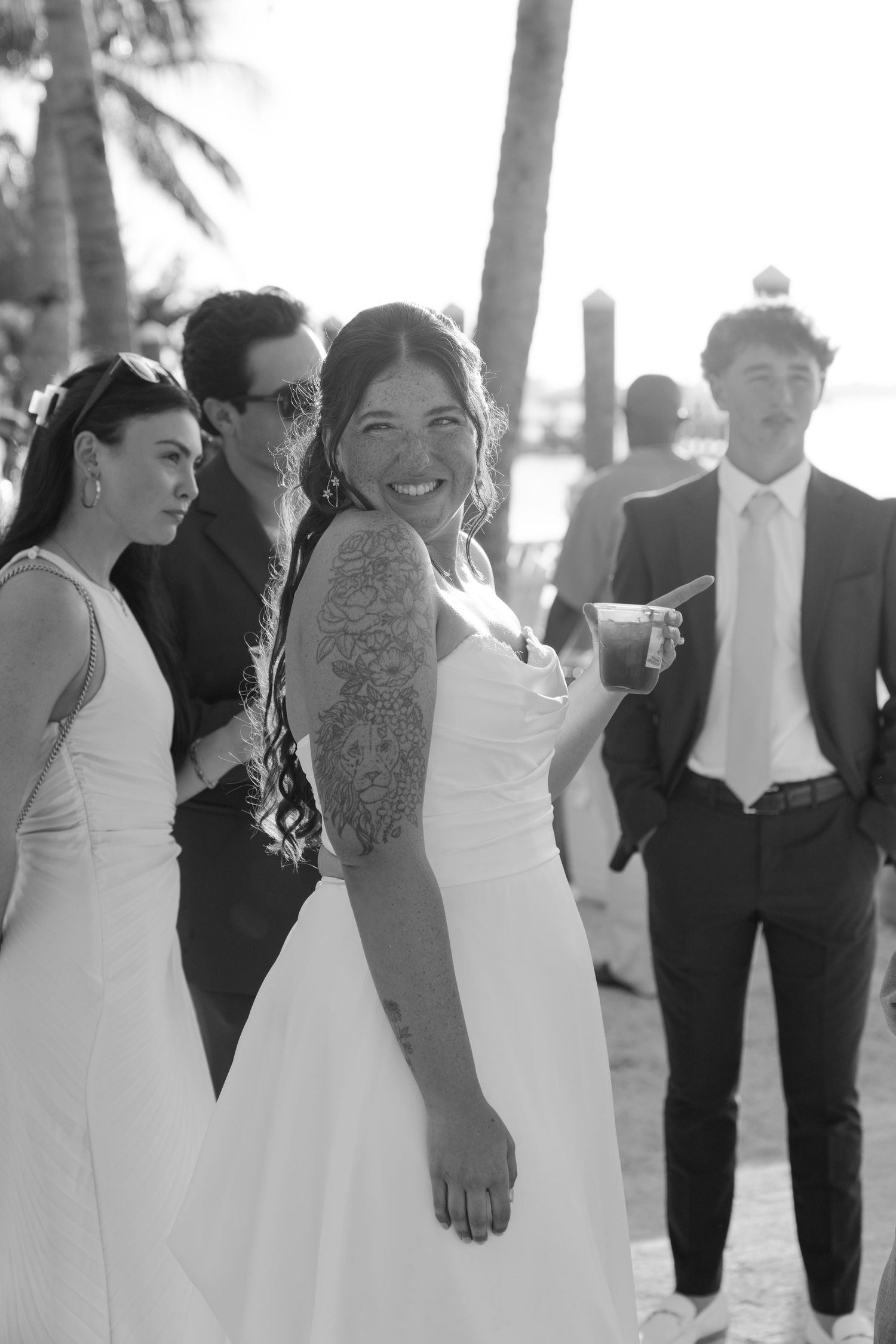 The image shows a group of people in formal attire walking together on a beach.