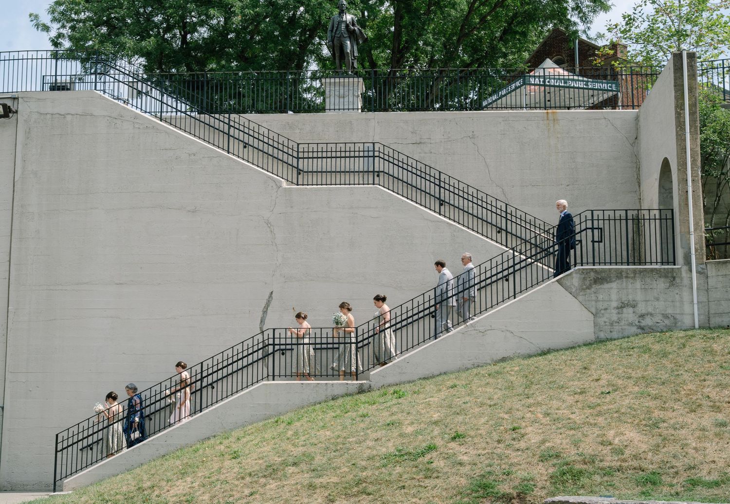 A group of people walking up a large concrete staircase with metal railings in an outdoor setting.