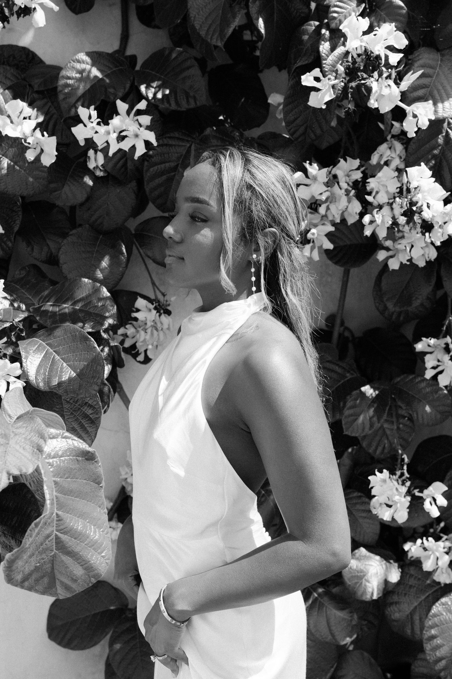 Elegant portrait against flowering vine wall in black and white photography.