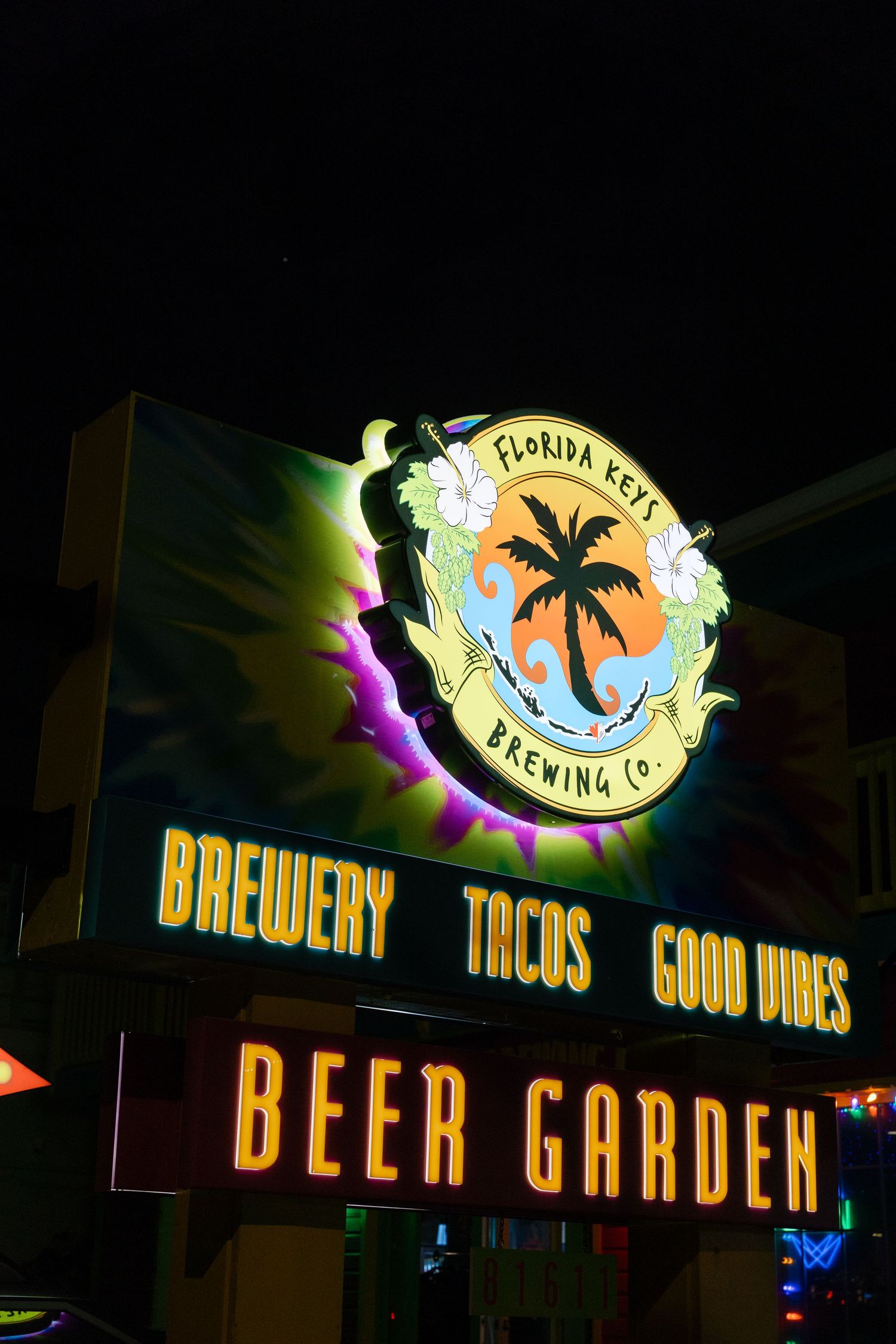 Illuminated beer garden sign for Florida Keys Brewing Company with palm tree logo at night.