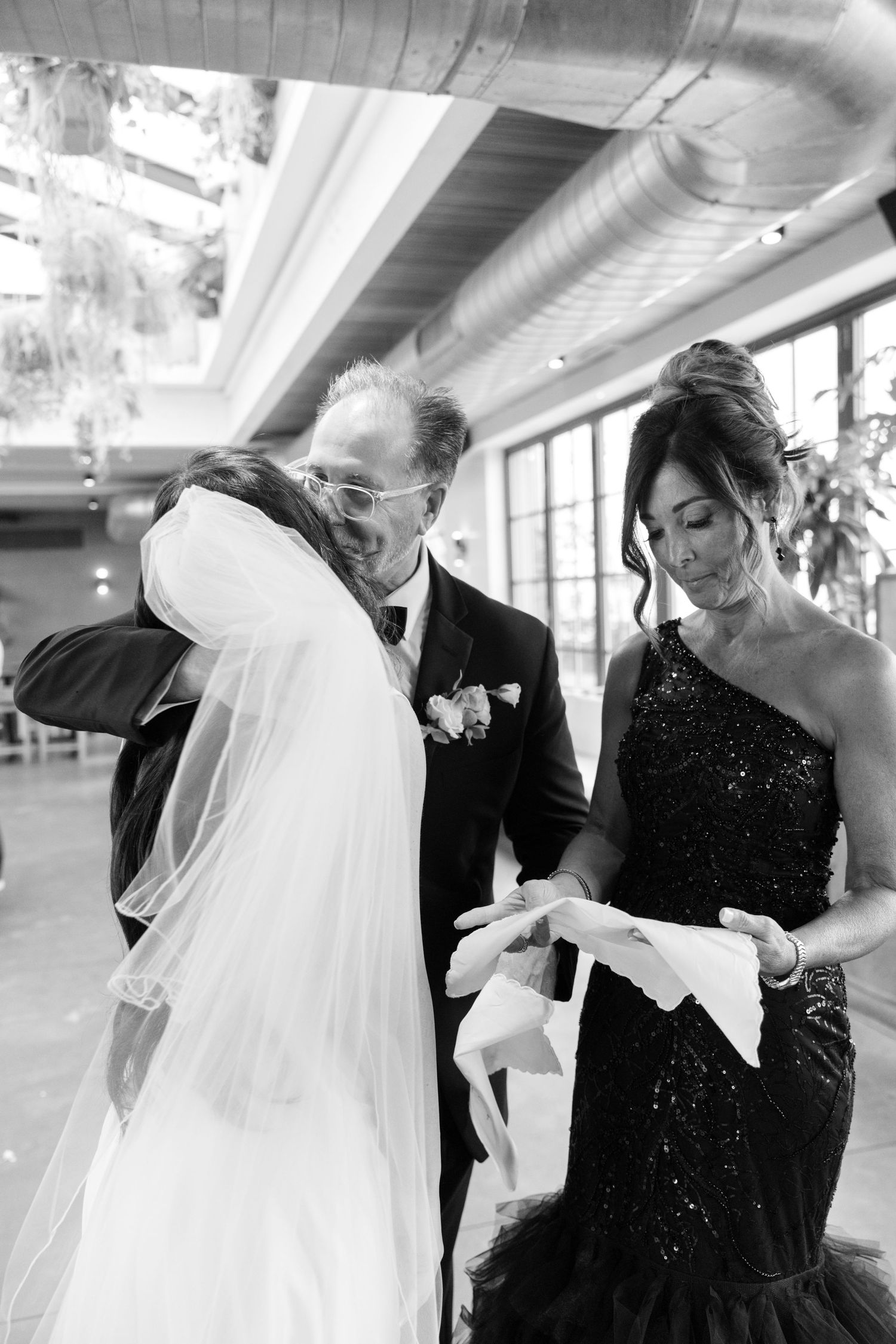 Wedding party members sharing emotional embraces during formal black and white portraits.