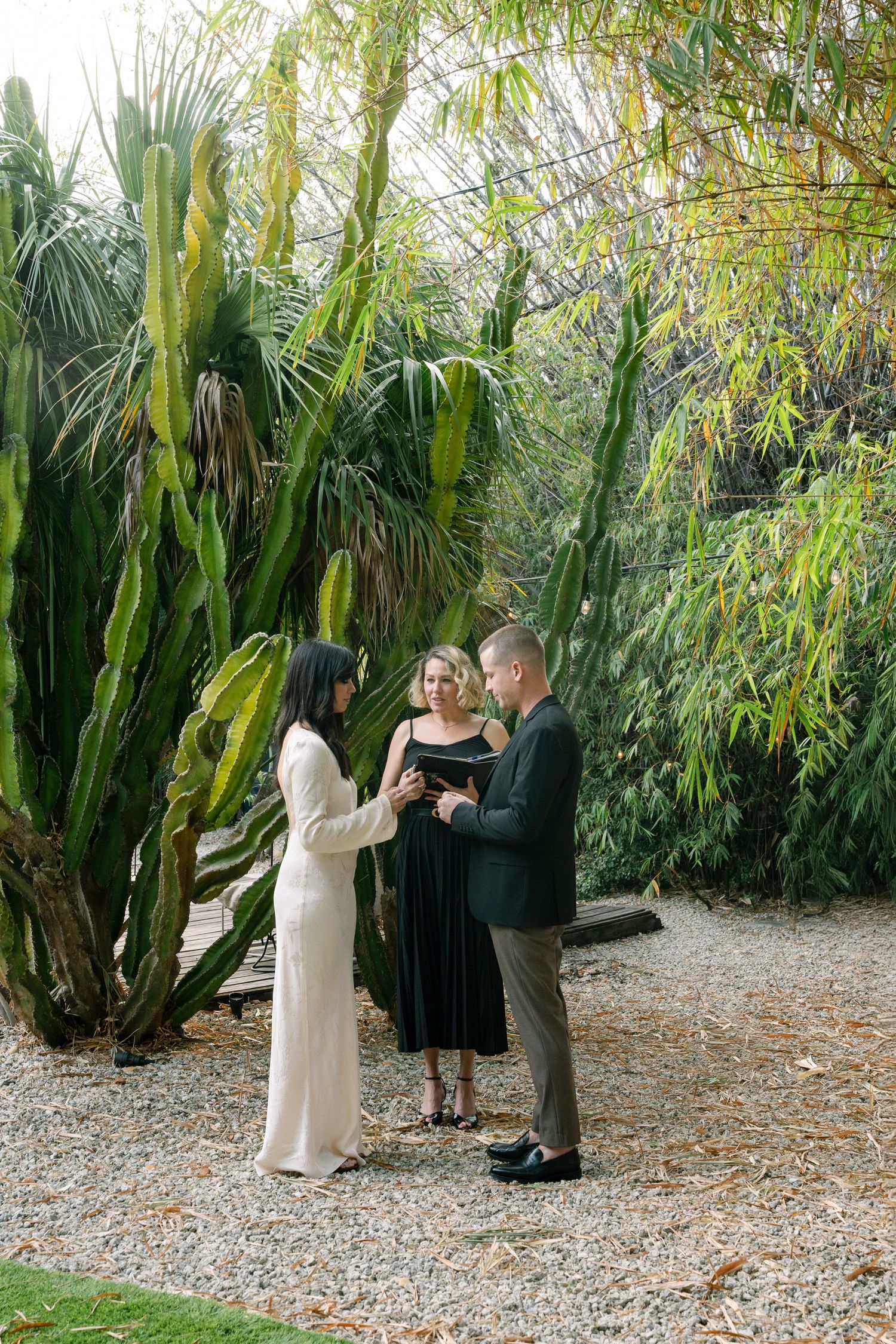 An intimate outdoor wedding ceremony takes place among lush tropical plants and bamboo.