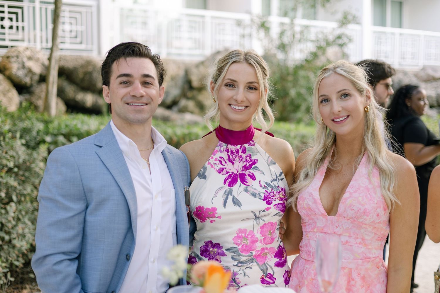 Wedding party in pink and blue attire posing together outdoors.