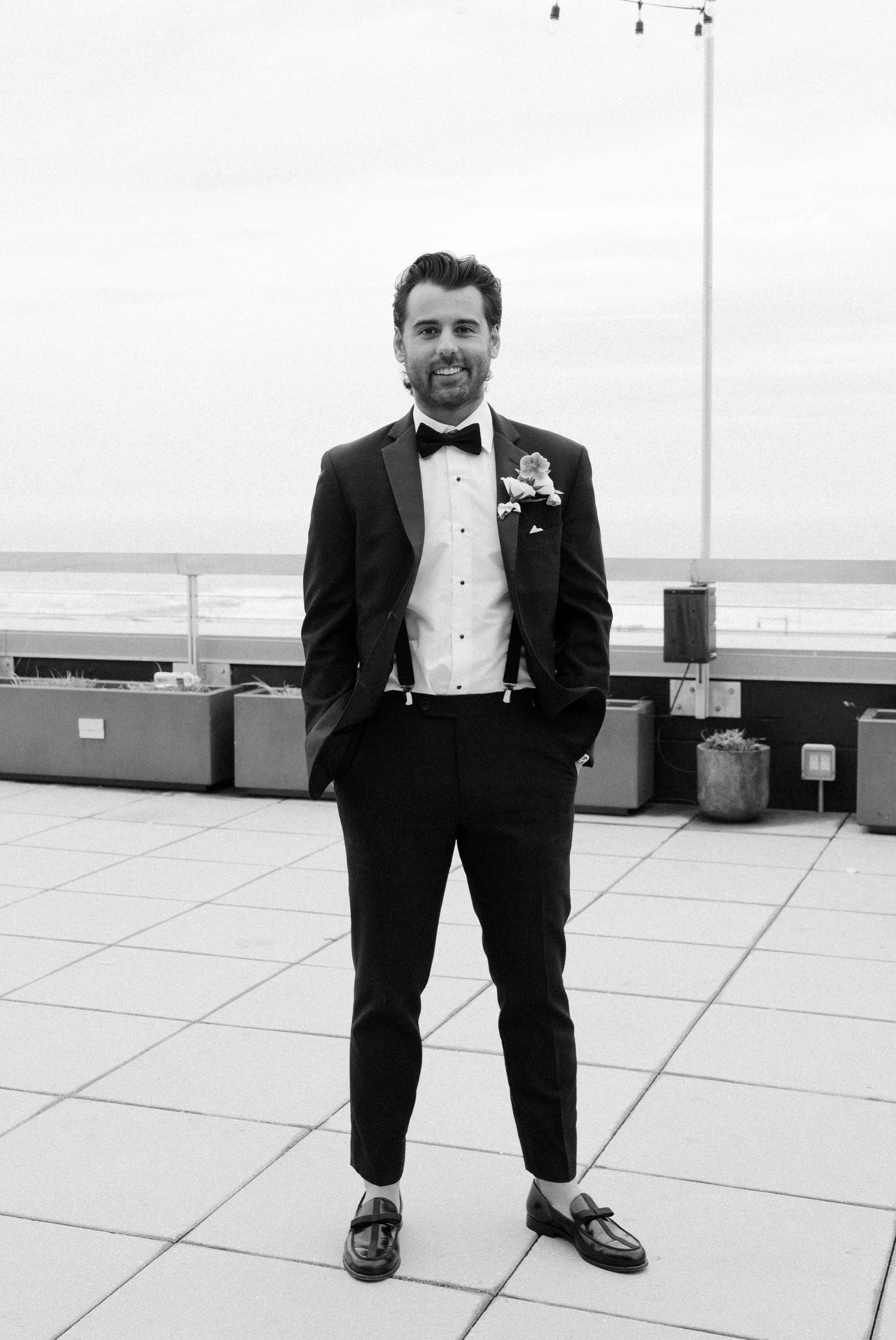 Formal wedding portrait on a rooftop terrace with ocean views in the background.