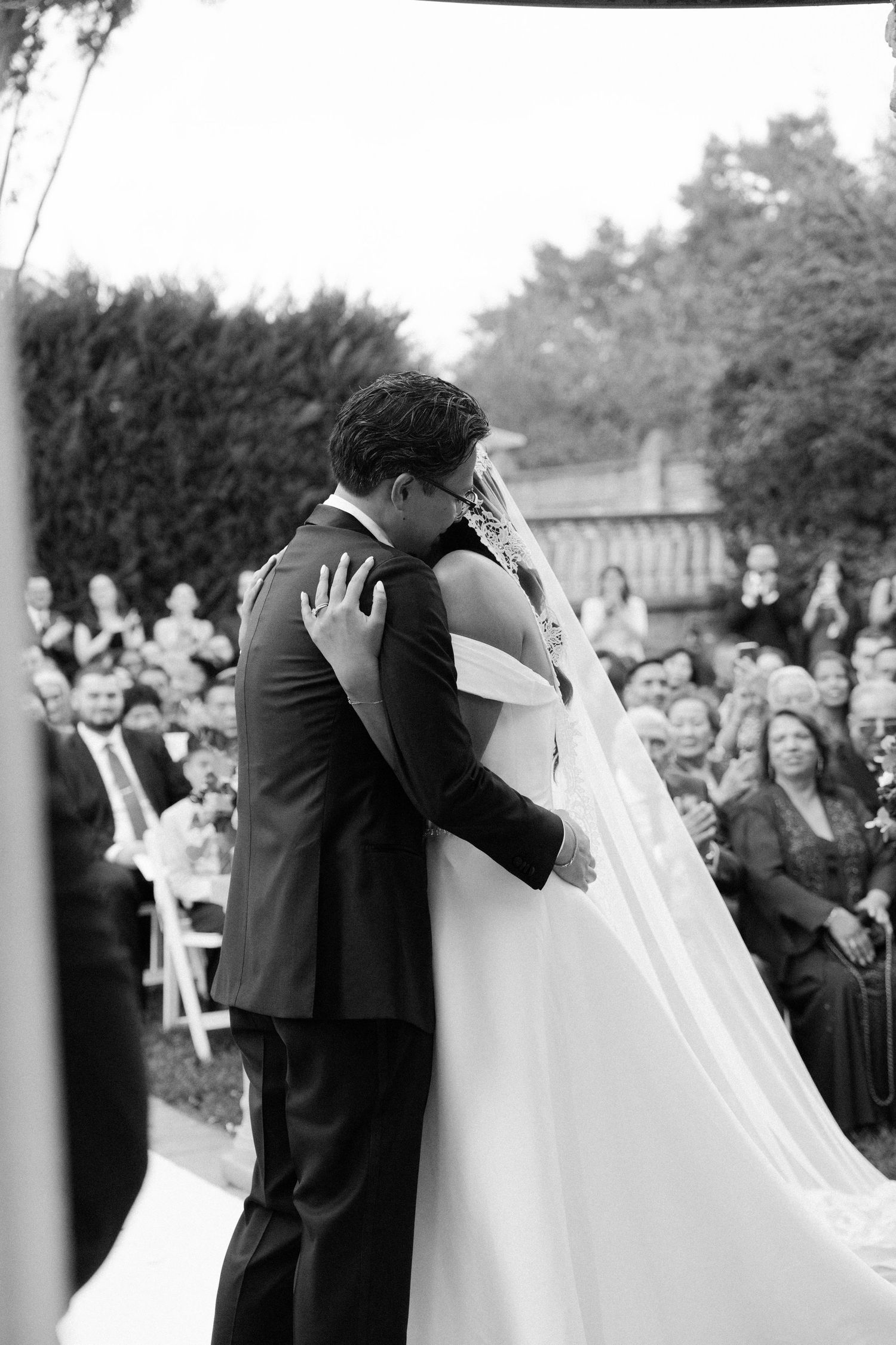 Black and white panoramic shot of outdoor wedding ceremony with guests in attendance.