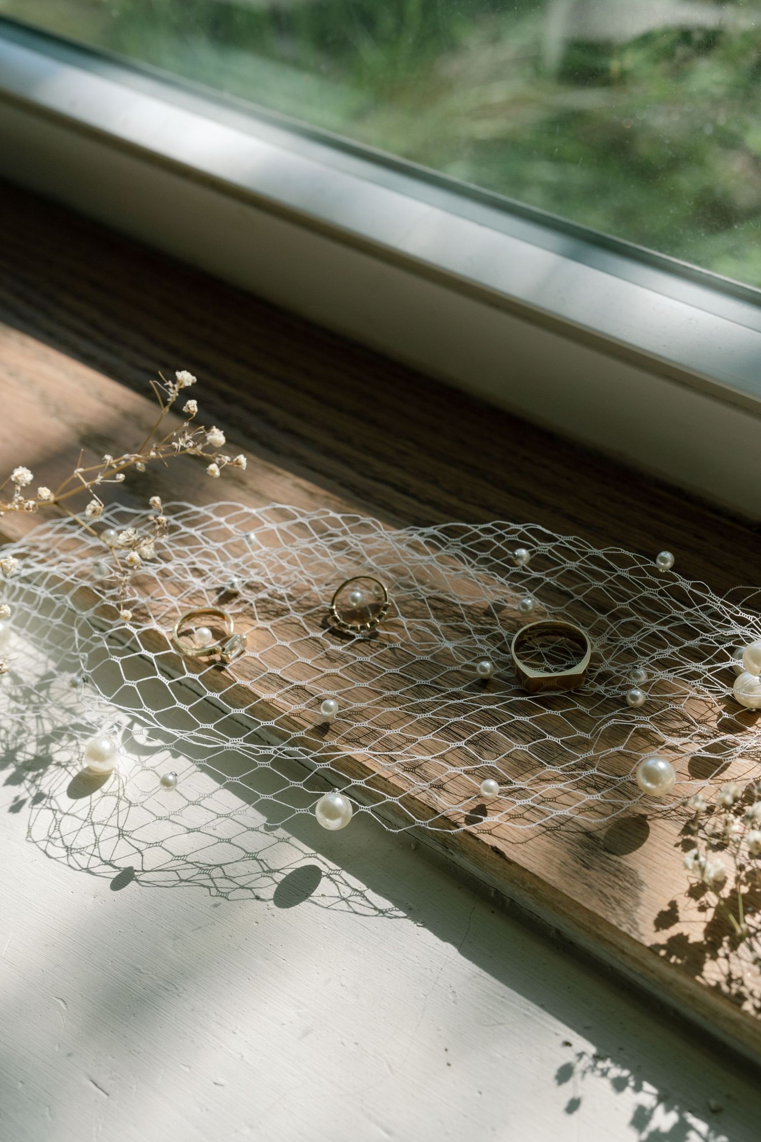 Delicate lace netting with dried flowers arranged along a windowsill in natural light.