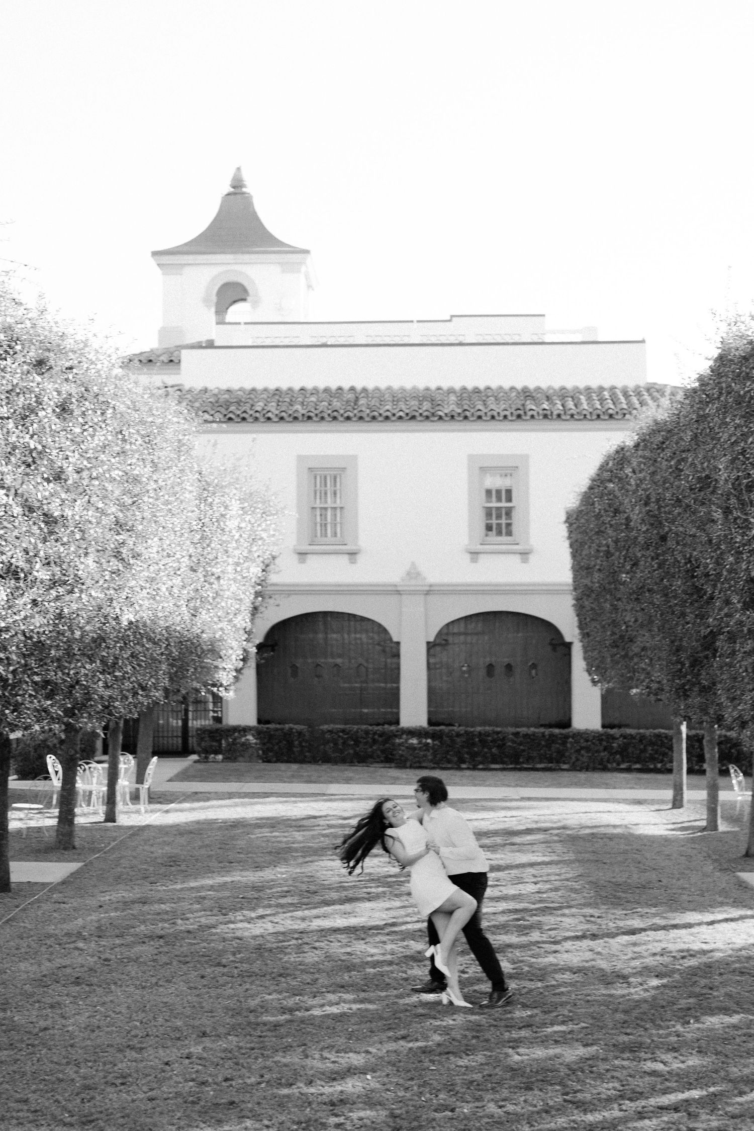 A sequence of black and white photos showing a person doing a cartwheel on a lawn in front of a white building.