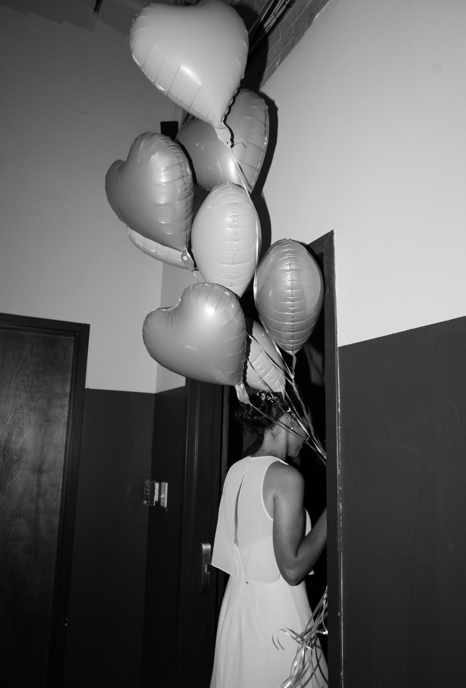 Black and white photos of heart-shaped balloons against a dark hallway.