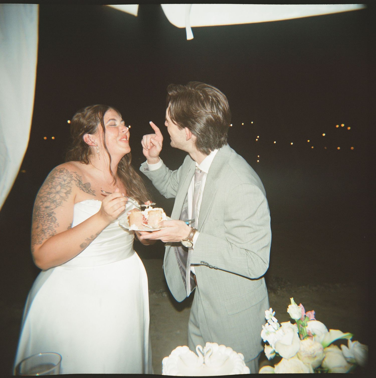 A bride and groom standing together and holding hands in a wedding setting with flowers.