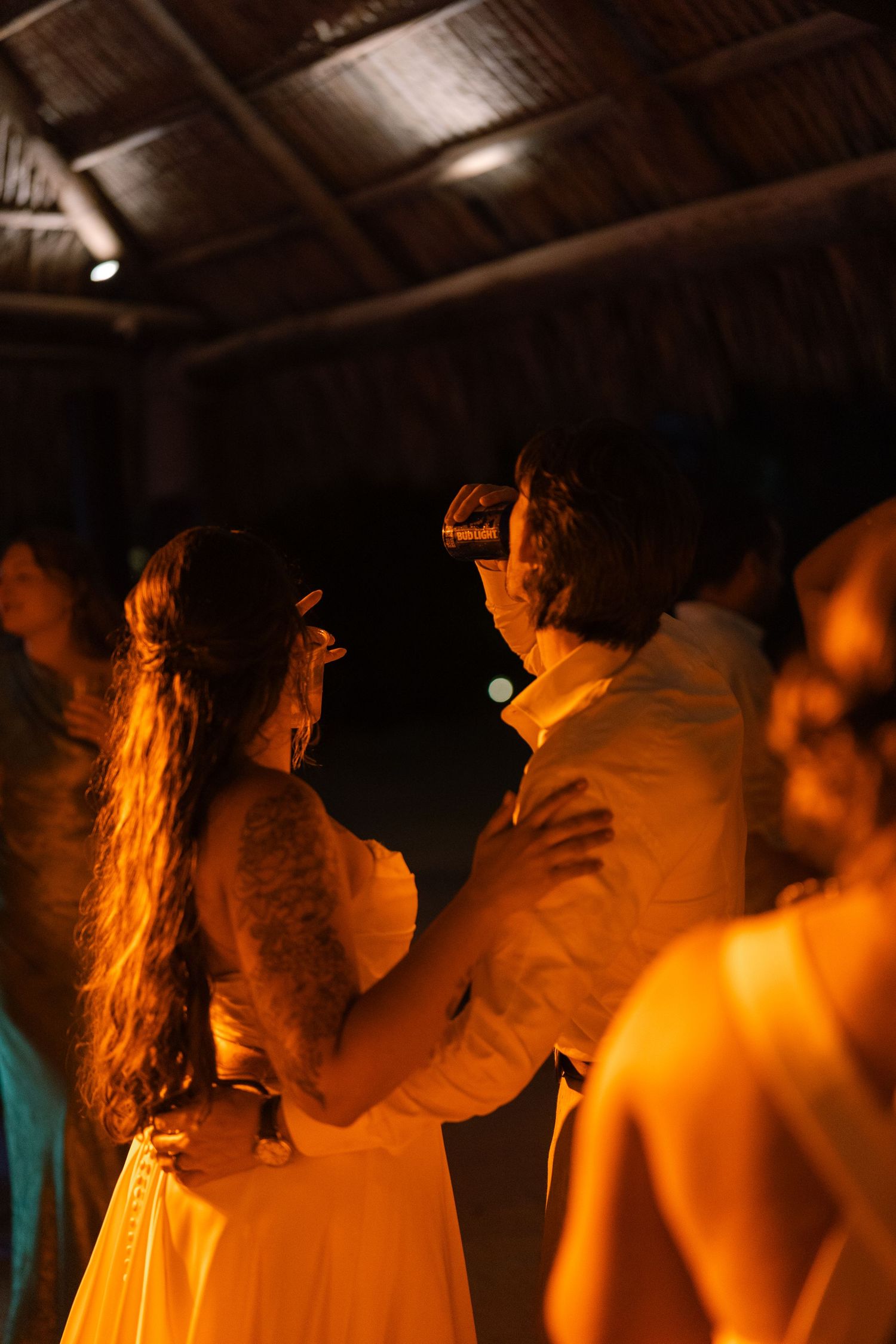 A group of people dancing closely together in a dimly lit room, with warm lighting creating a festive atmosphere.
