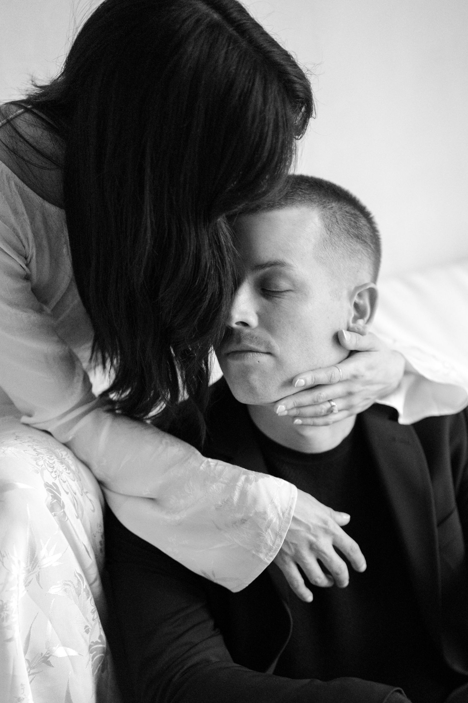 Two figures in contrasting black and white clothing embracing in an intimate artistic photoshoot.