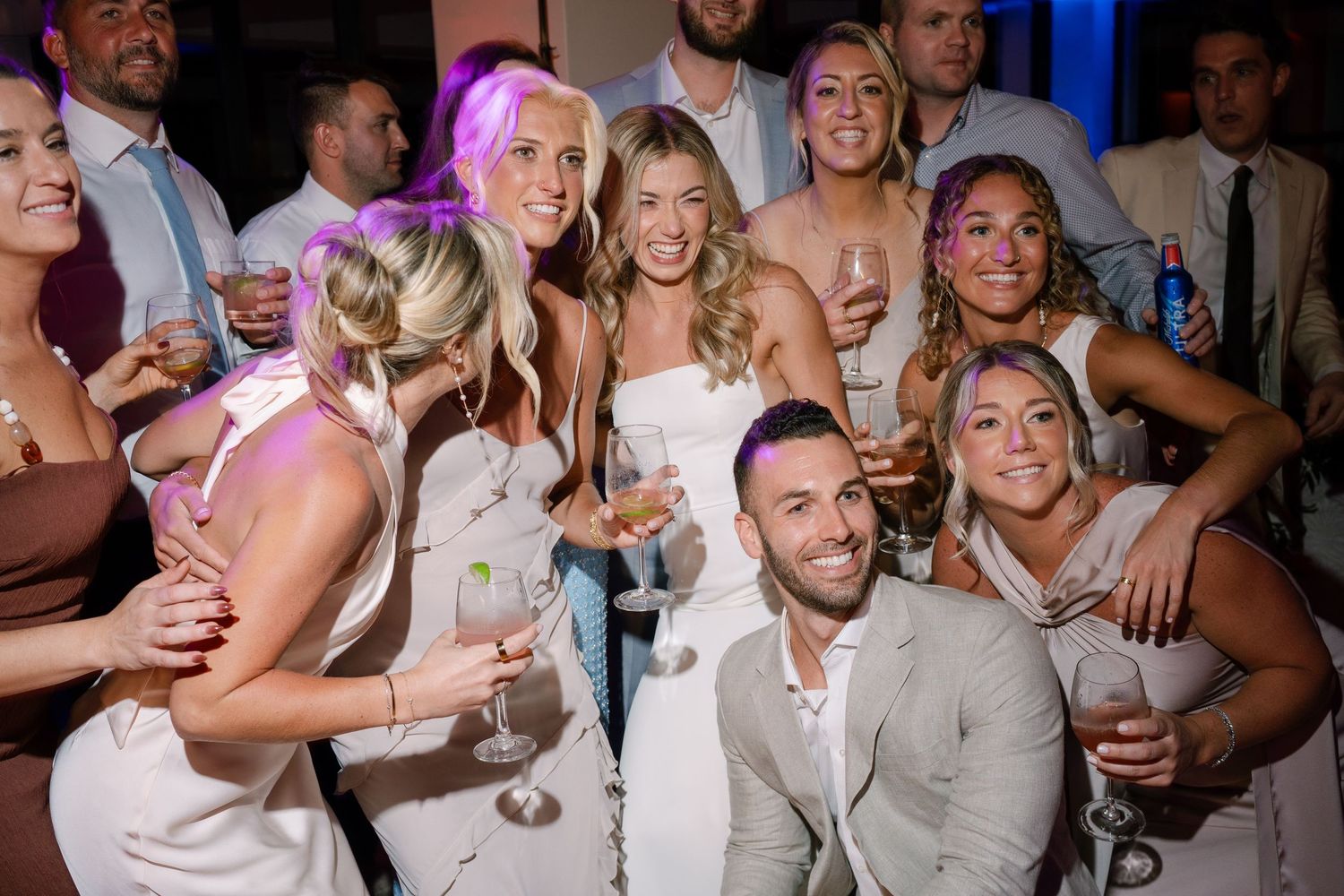 Lively wedding reception party scene with guests celebrating and raising glasses.