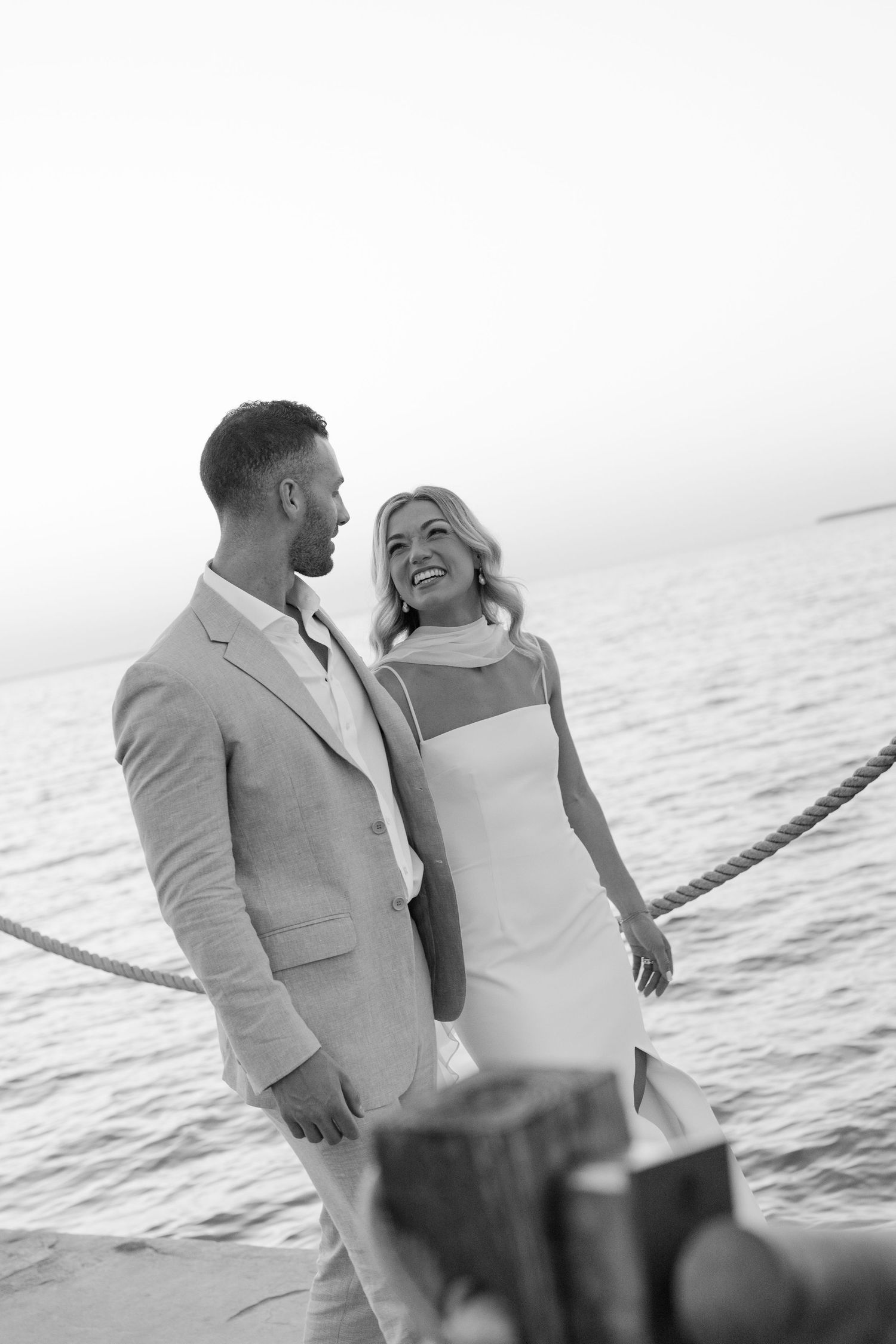 Romantic black and white photos of couple sharing intimate moments by the ocean.