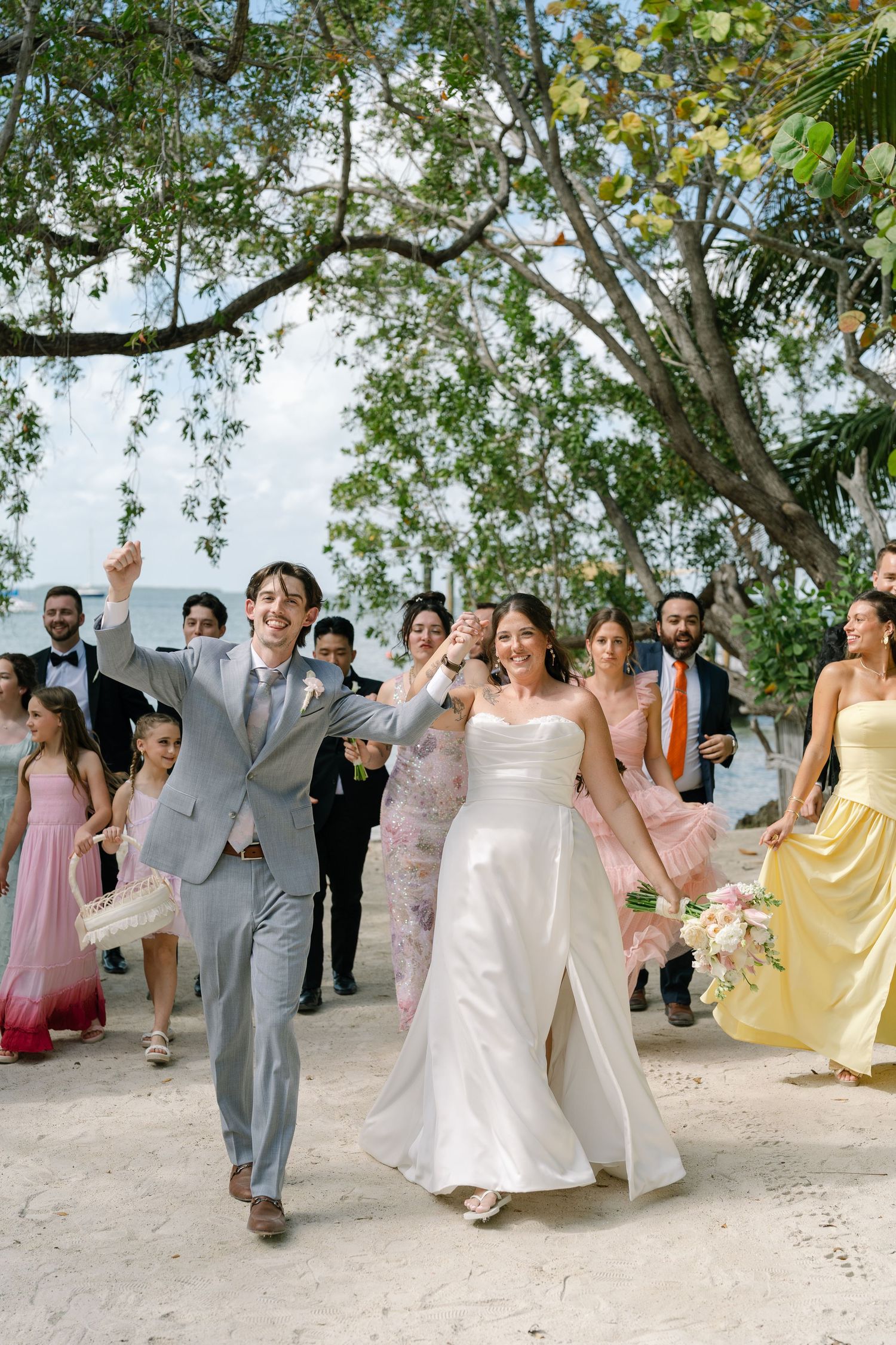 A wedding party walking down a path surrounded by lush greenery.