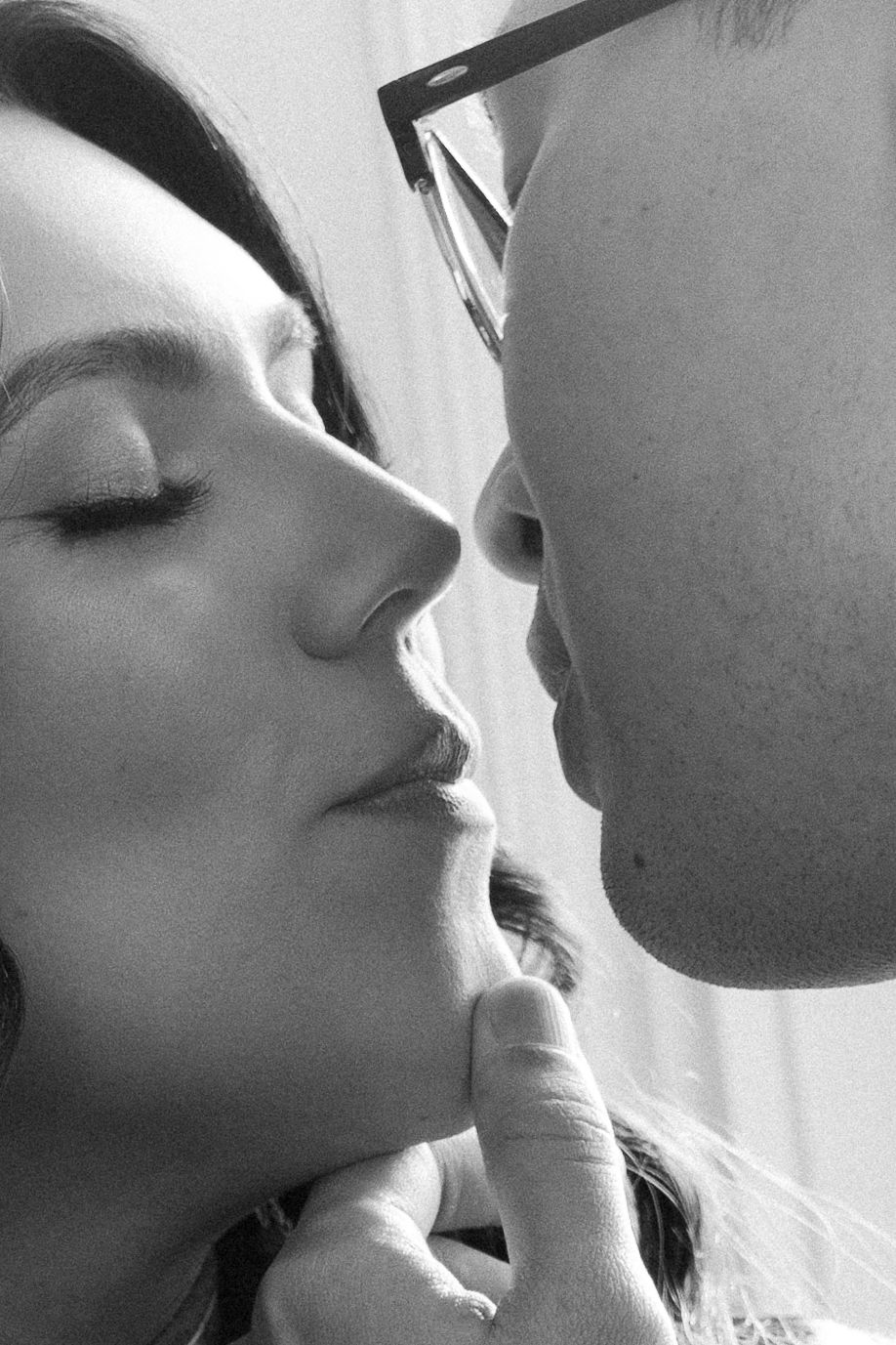 A romantic black and white close-up photo of a tender kiss moment between two people.