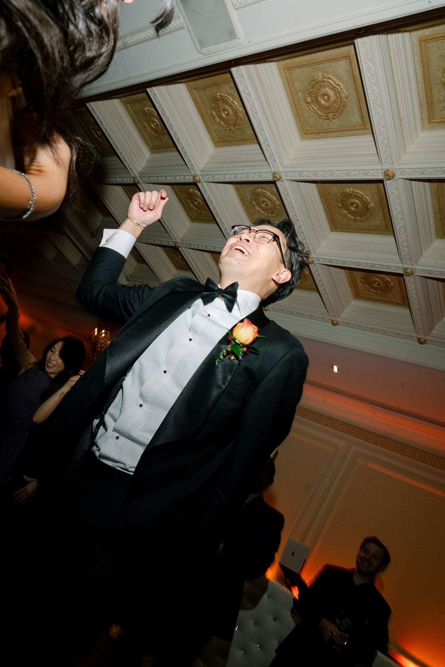 People in formal attire dancing and celebrating at an elegant indoor reception venue.