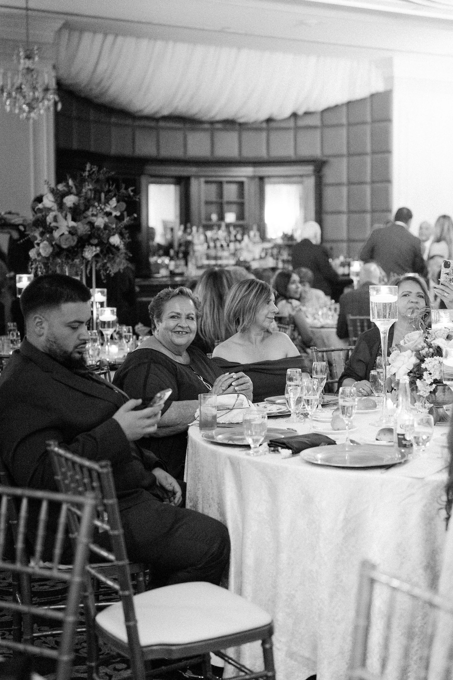 Wedding reception venue with guests seated at round tables with white linens.