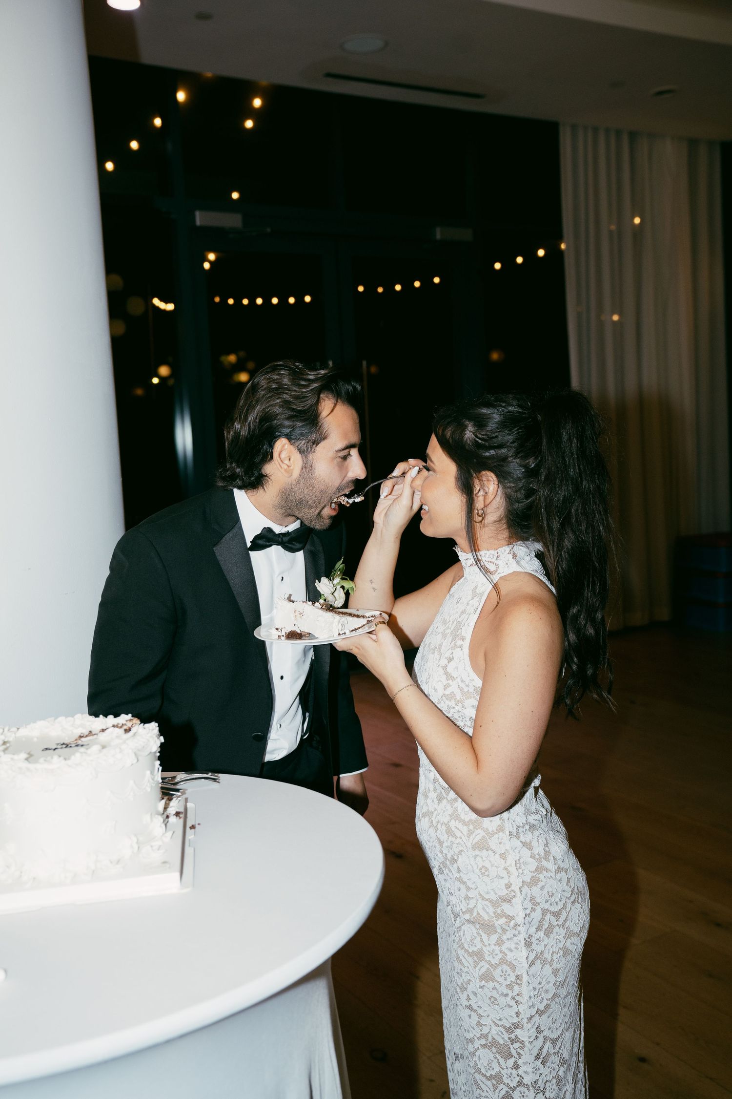 Couple sharing a playful cake-cutting moment at their wedding reception.