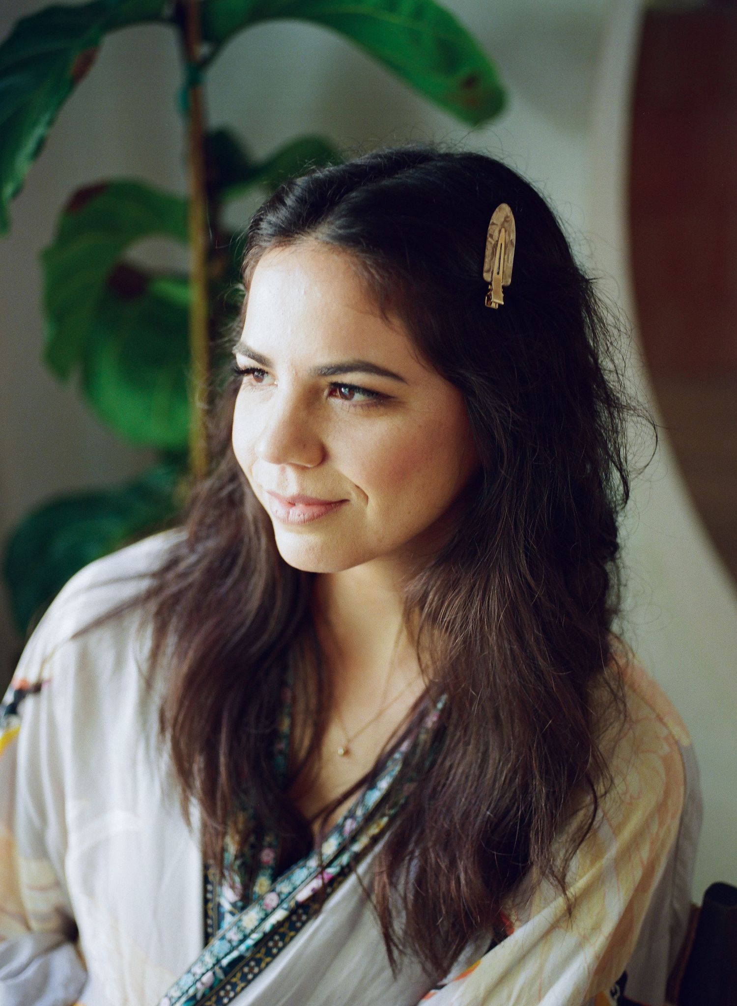 A series of portraits showing someone with long dark hair wearing a white top and delicate jewelry against a soft background.