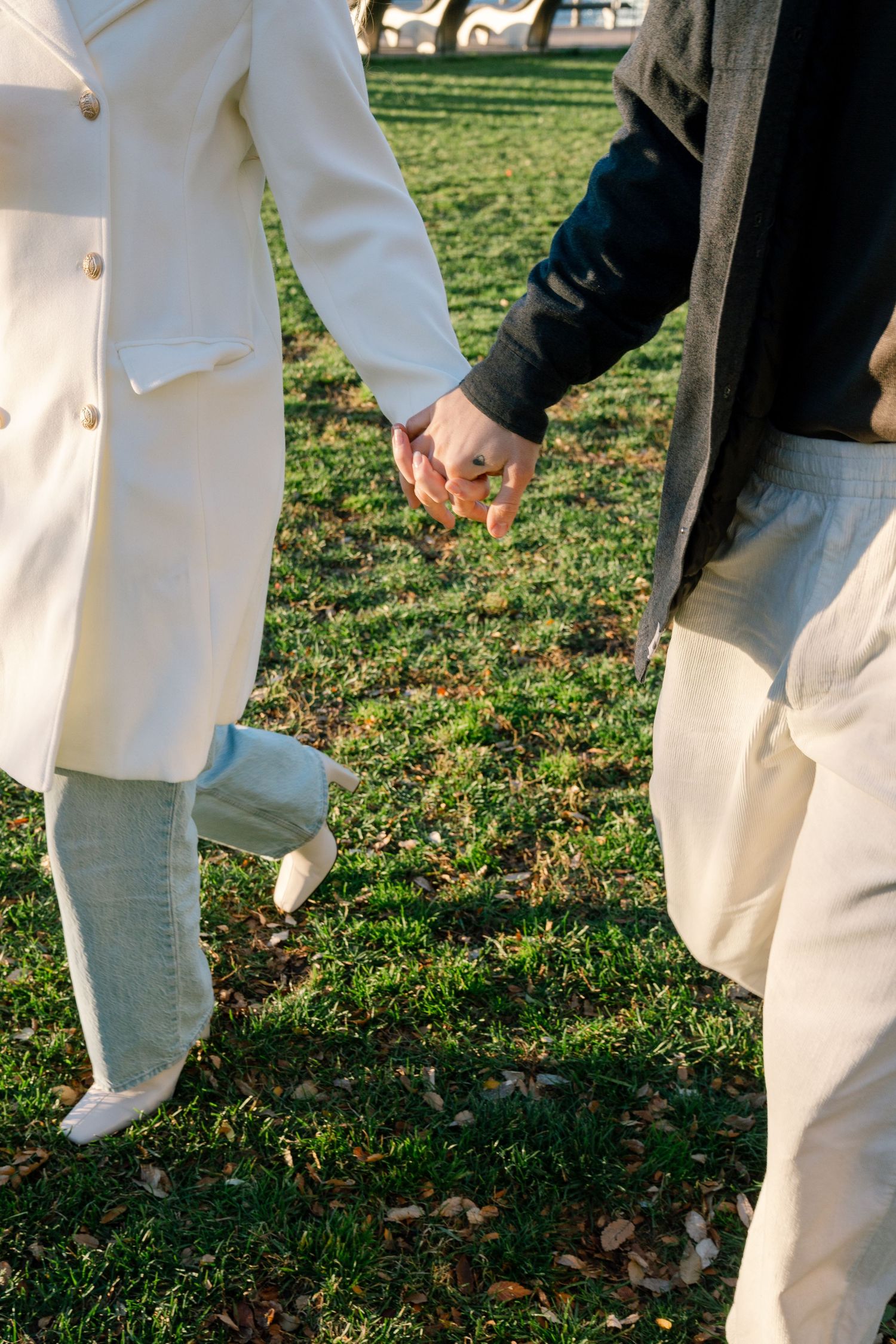 Close-up of people's legs walking on grass, wearing white and dark clothing.