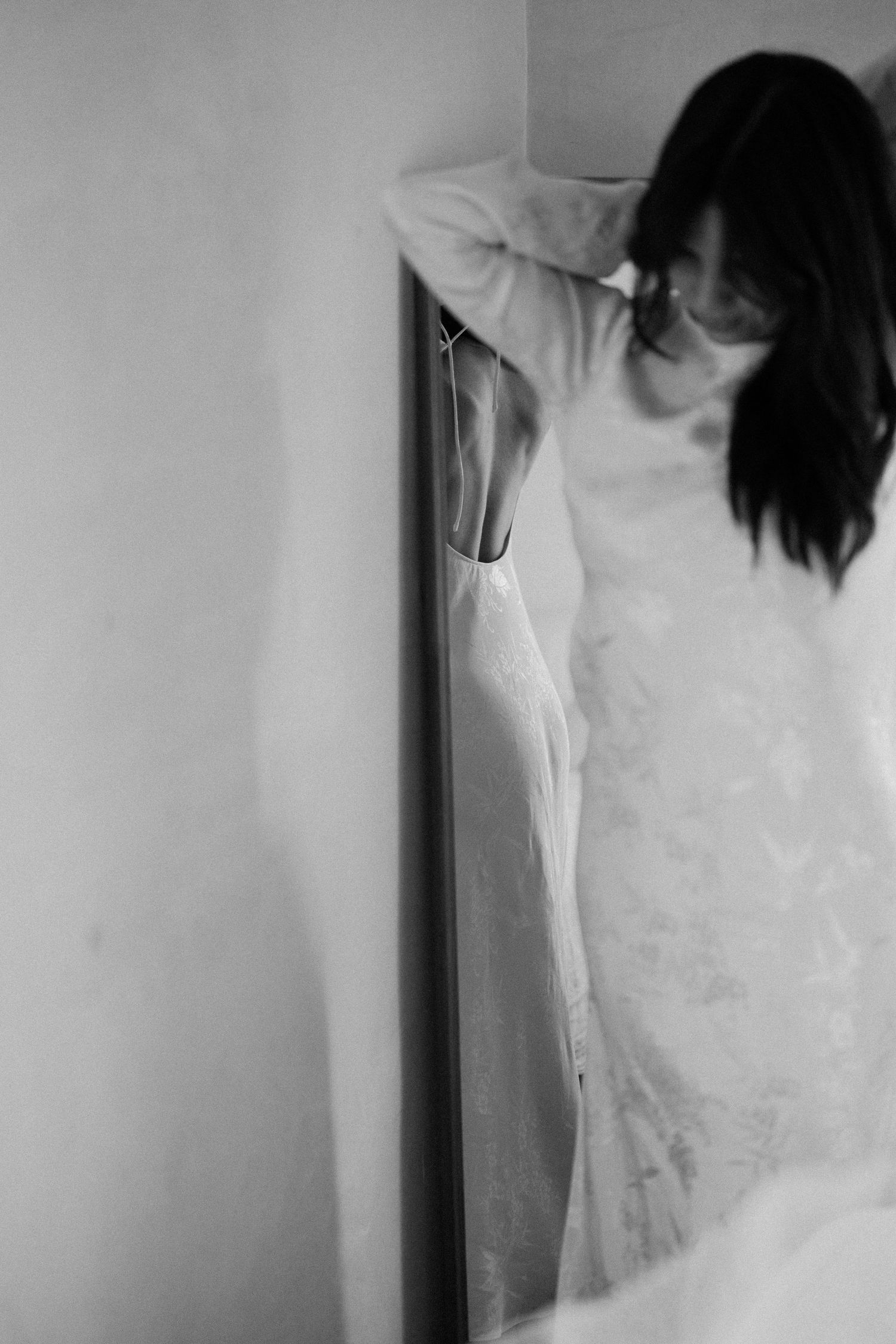 Close-up details of a white dress hanging against a light colored wall.