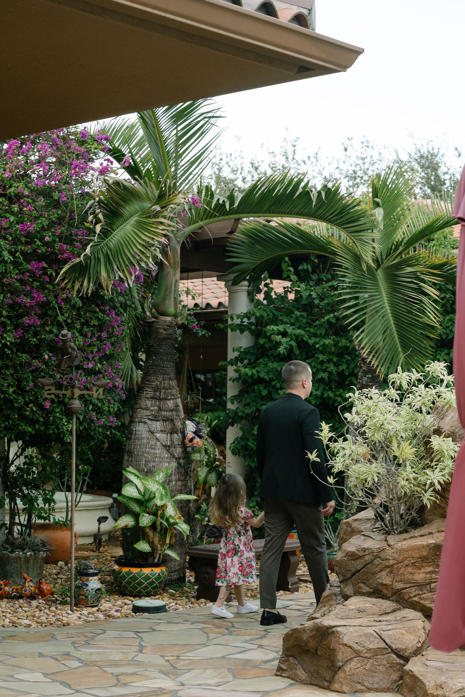 Garden patio with palm trees, stone features and tropical landscaping.