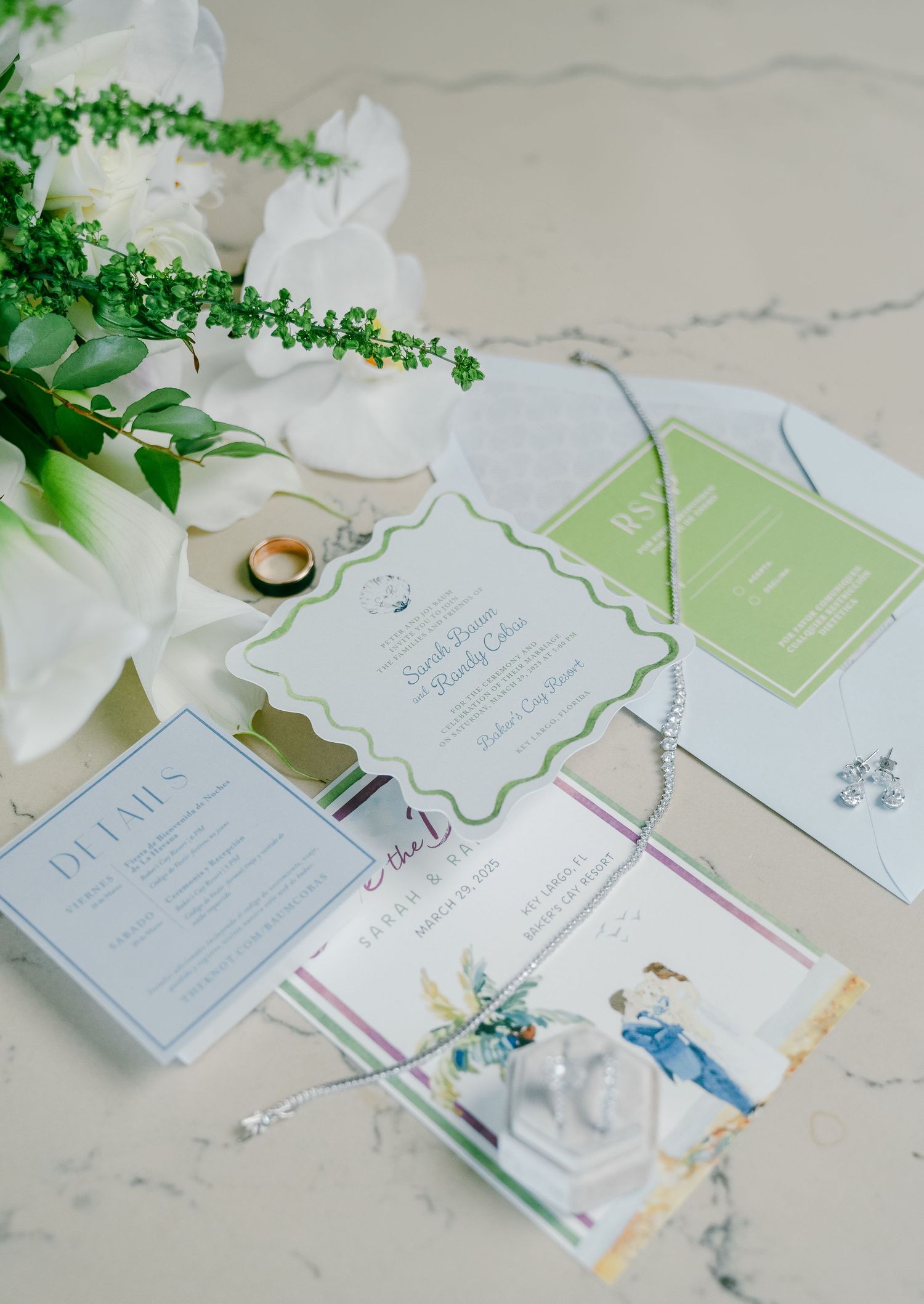 Wedding invitation suite with mint green and white cards displayed on marble surface with delicate floral accents.