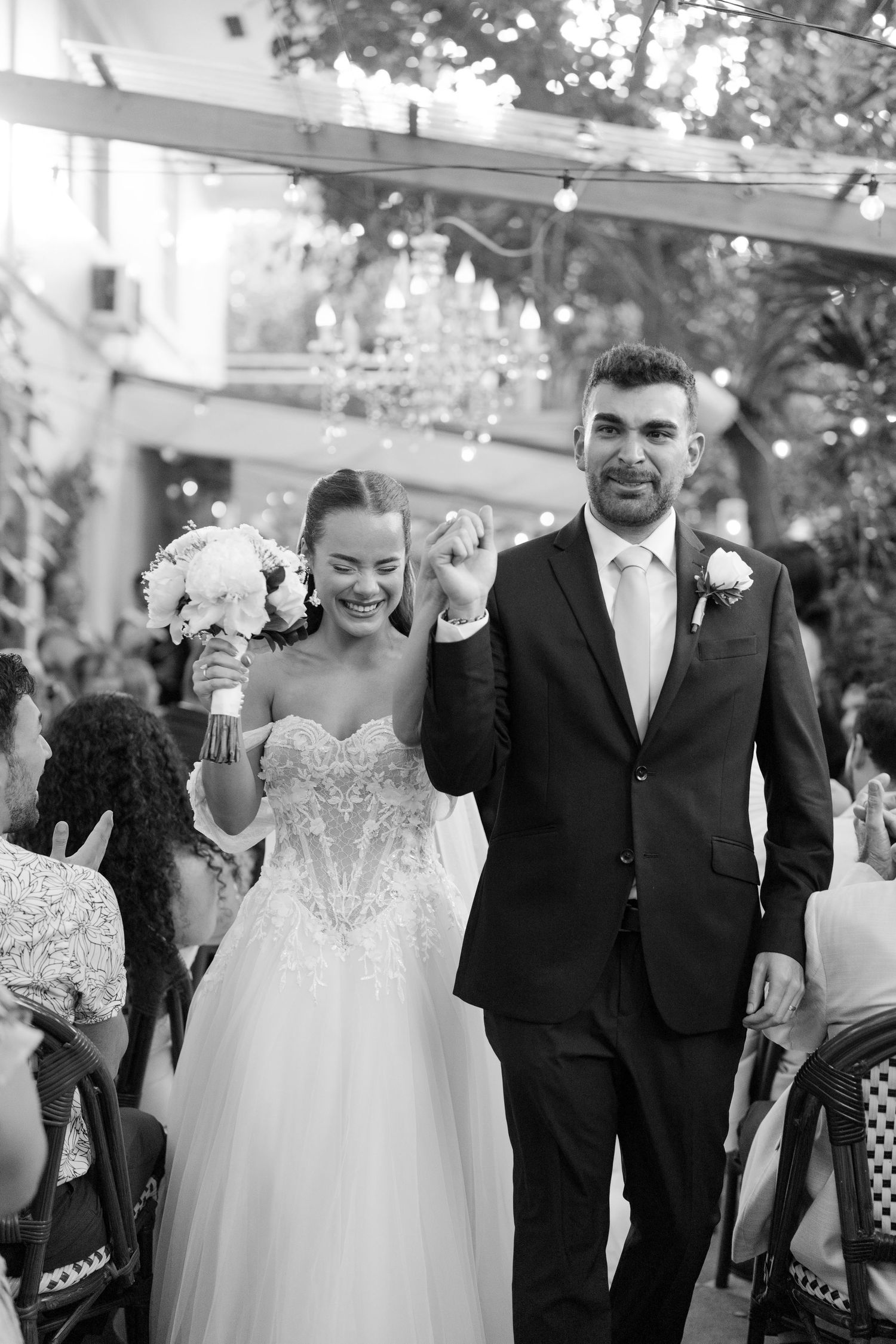 Black and white photo of a joyful bride and groom walking down the aisle after their wedding ceremony.