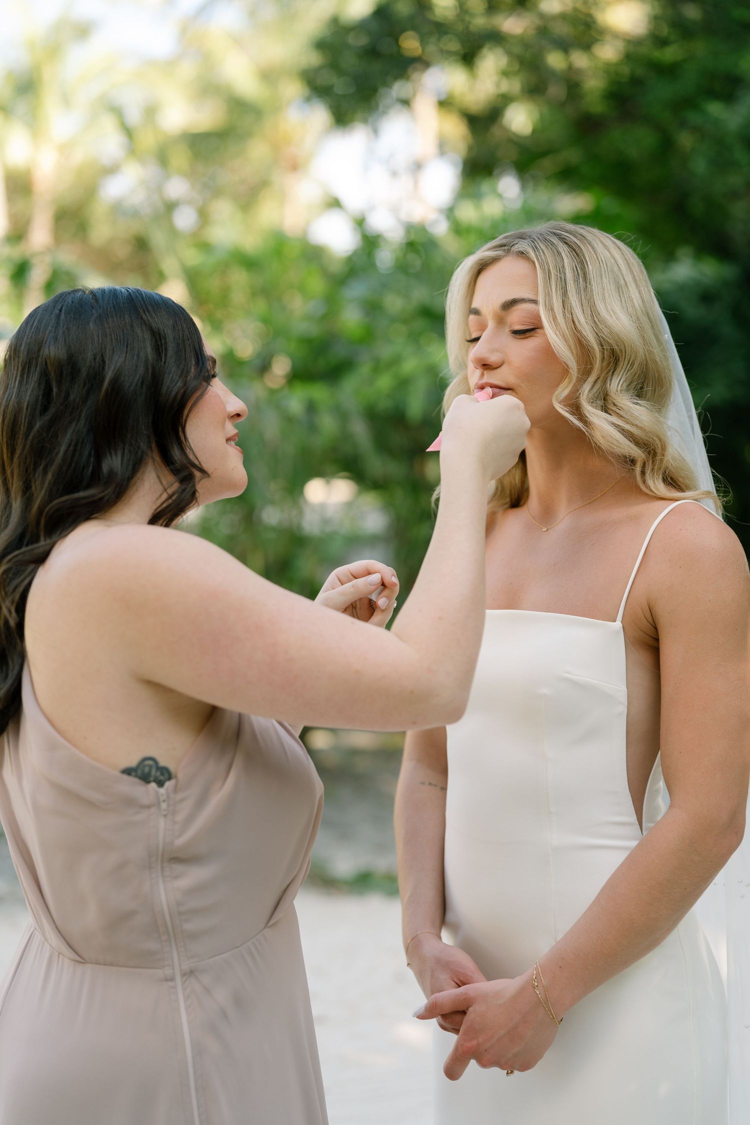 A touching pre-wedding moment as final makeup touches are applied outdoors.