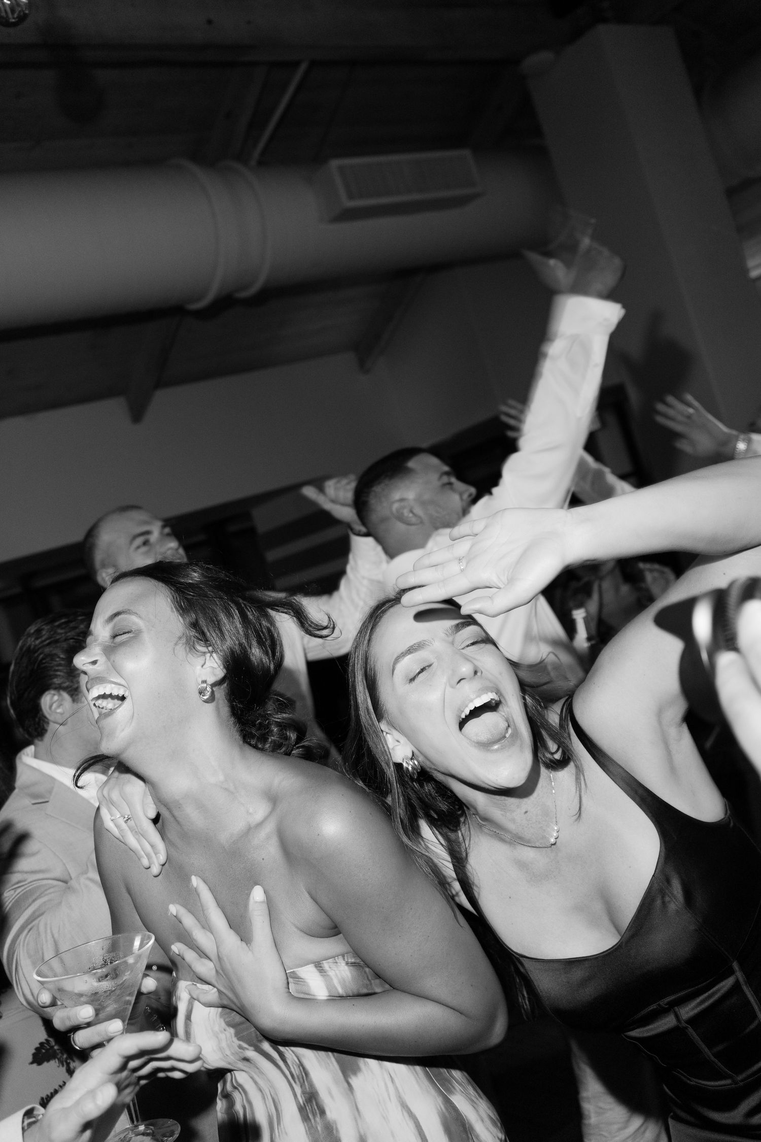 Group of wedding guests dancing and celebrating enthusiastically on dance floor.