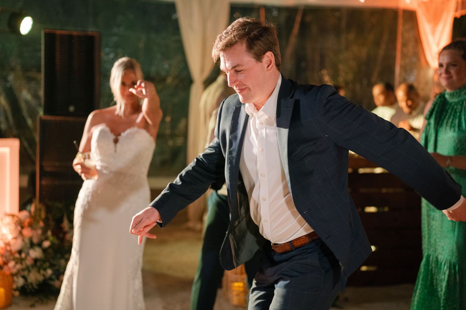Wedding reception dance floor with warm lighting and people dancing in formal attire.