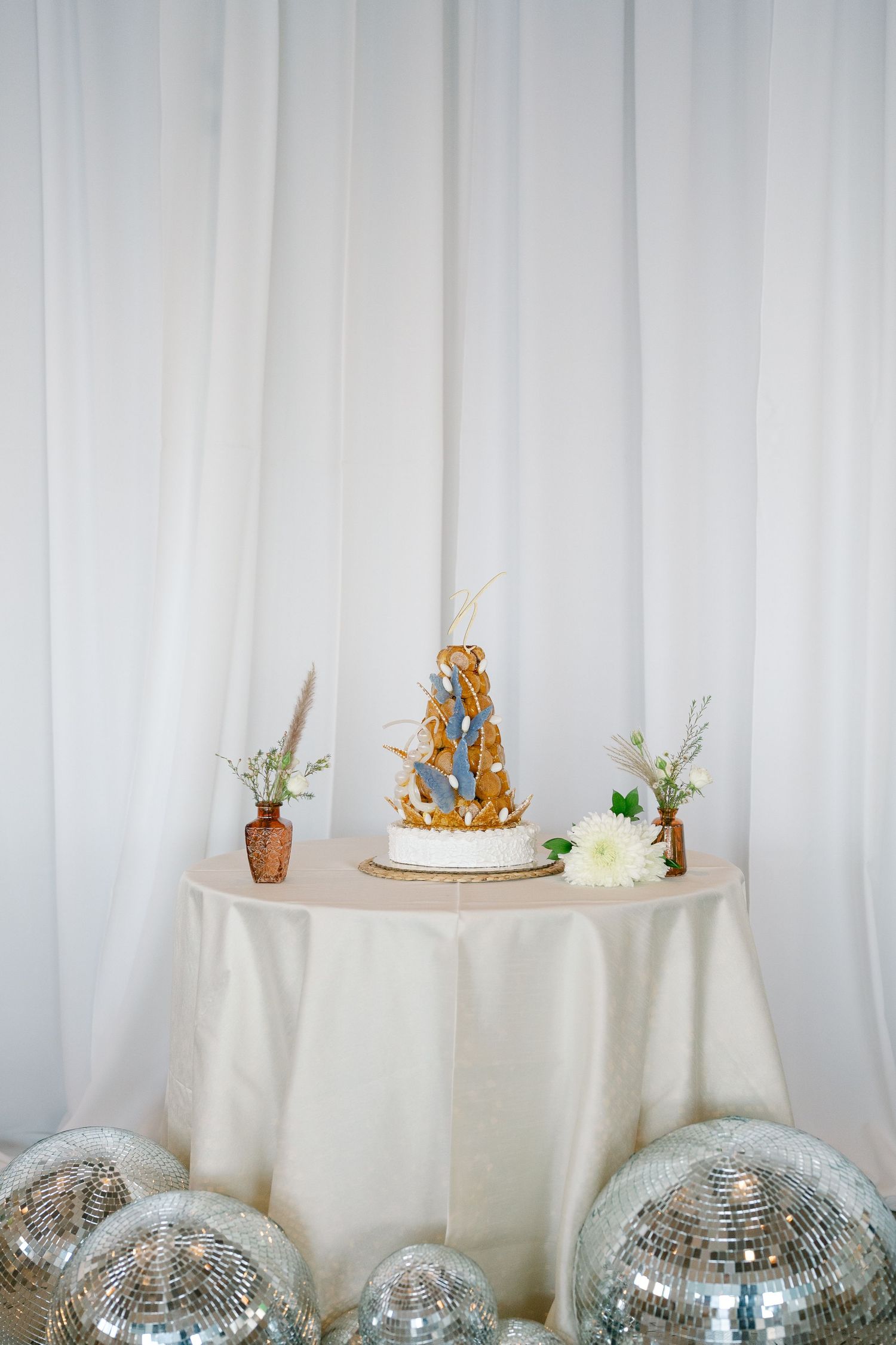 White tablecloths and disco balls create an elegant party setup with small decorative elements and floral accents.