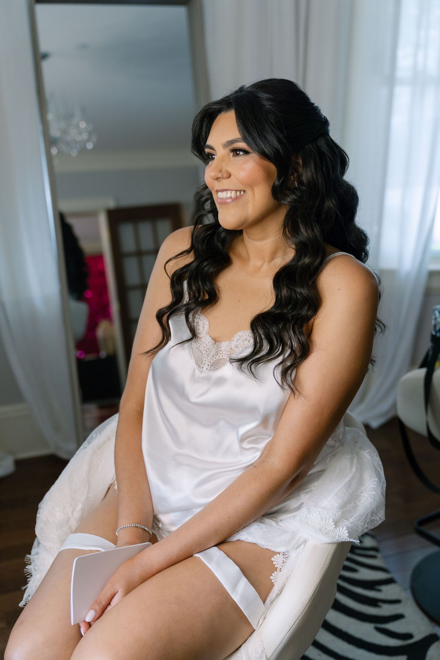 Bridal boudoir session featuring white satin robe and romantic lighting in an elegant setting.