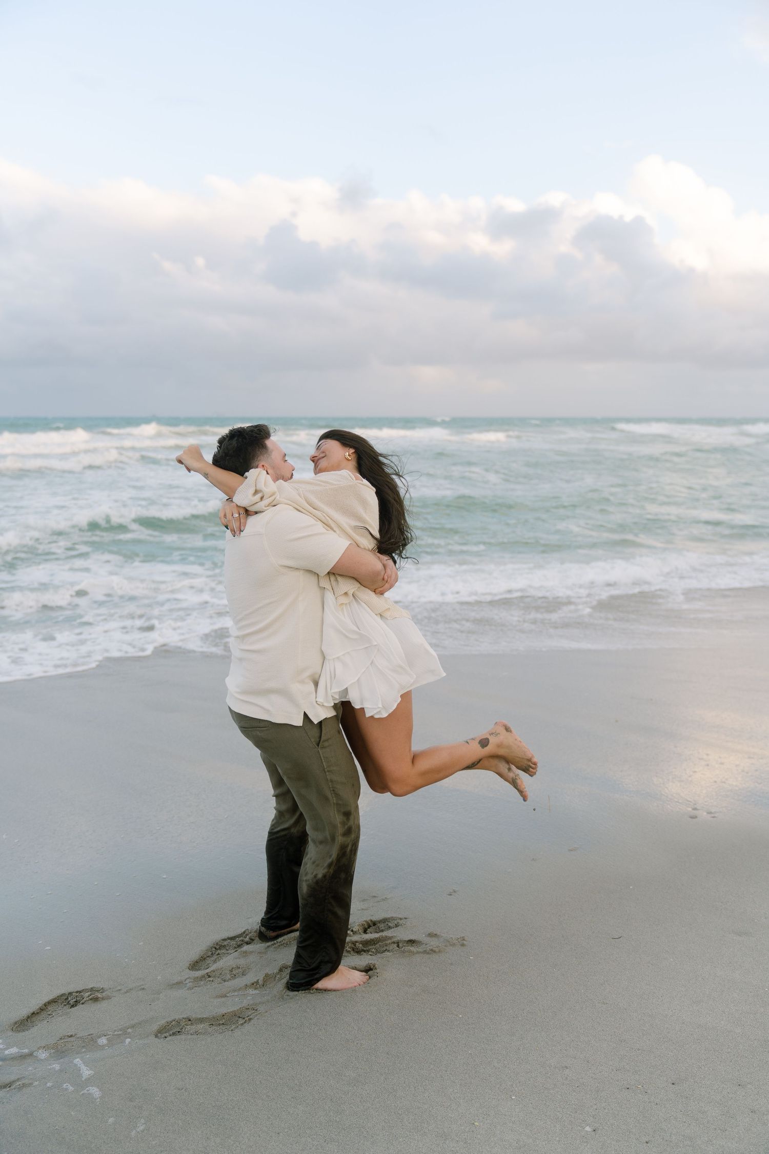 Romantic dance sequence showing two people embracing and spinning together on a sandy beach at dusk.