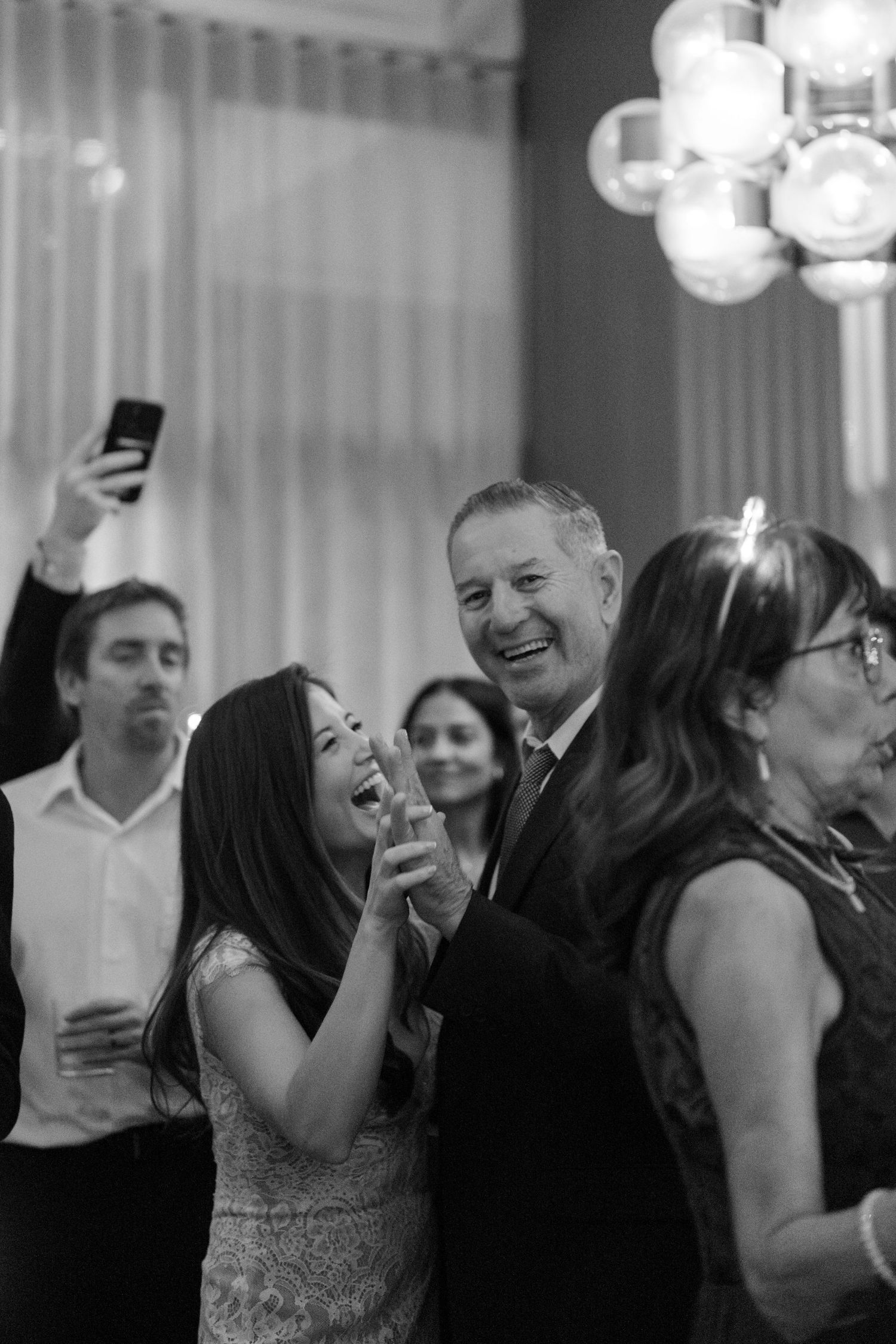 People laughing and celebrating at an elegant party under crystal chandeliers in a sequence of candid shots.