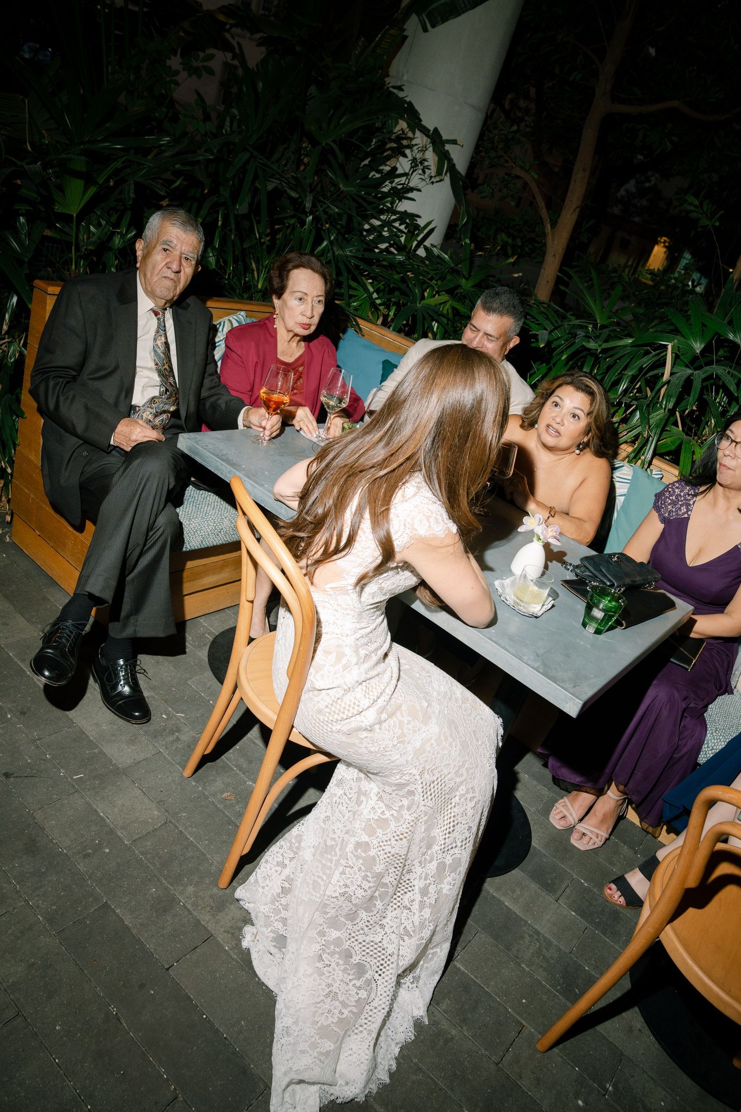Wedding guests enjoy a lively outdoor reception with seating arranged on a patio area.