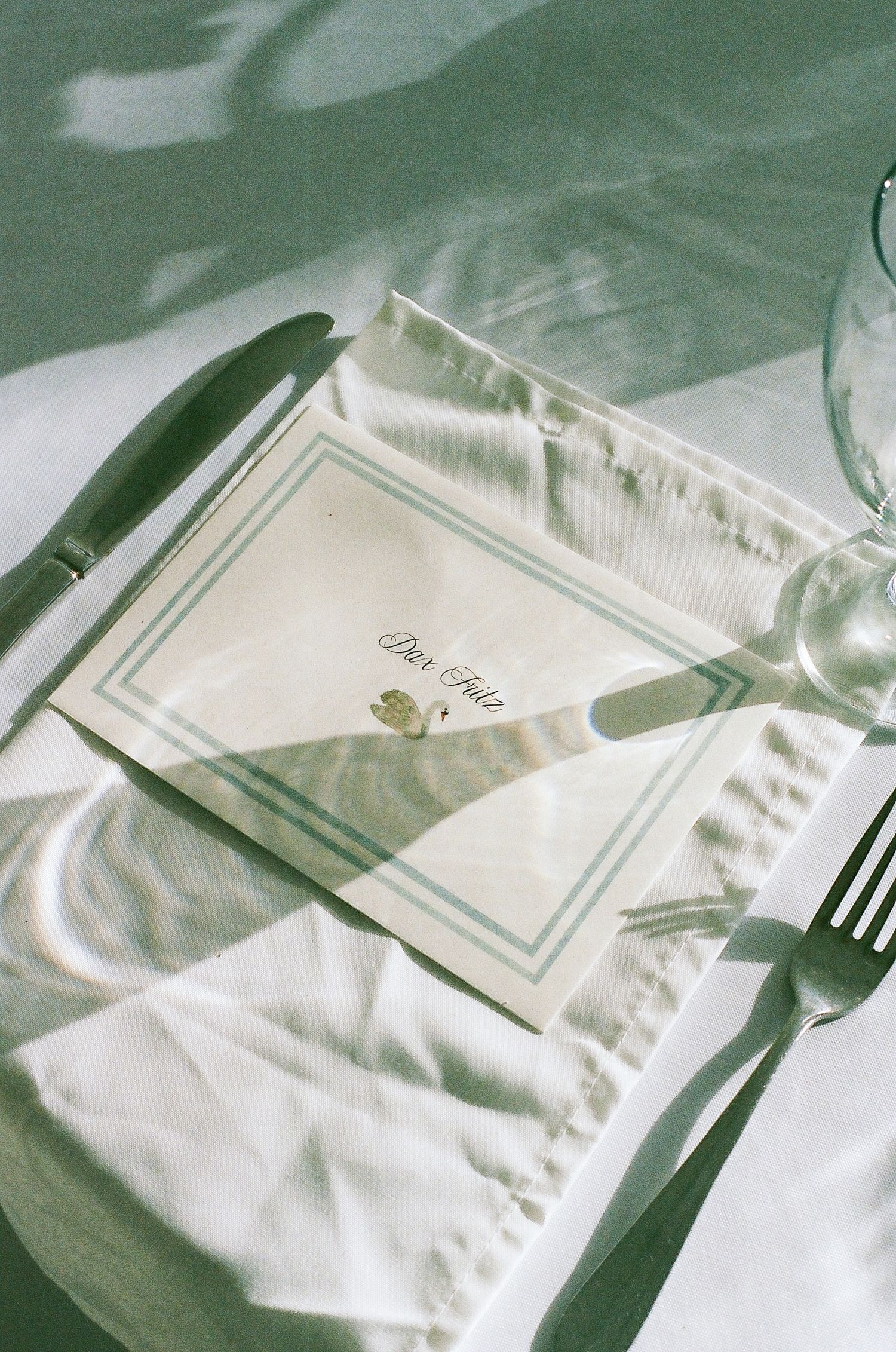 A place setting with a menu card and utensils on a table with a white tablecloth.