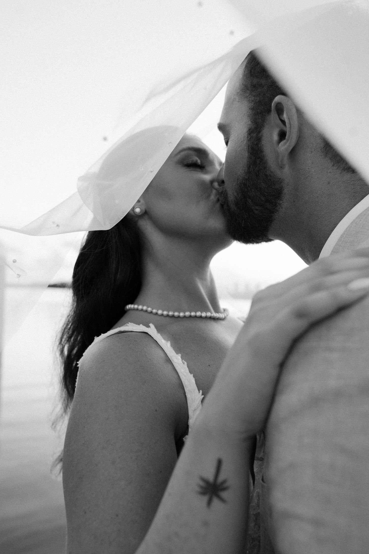 Black and white romantic wedding photo sequence showing a couple sharing an intimate kiss outdoors.