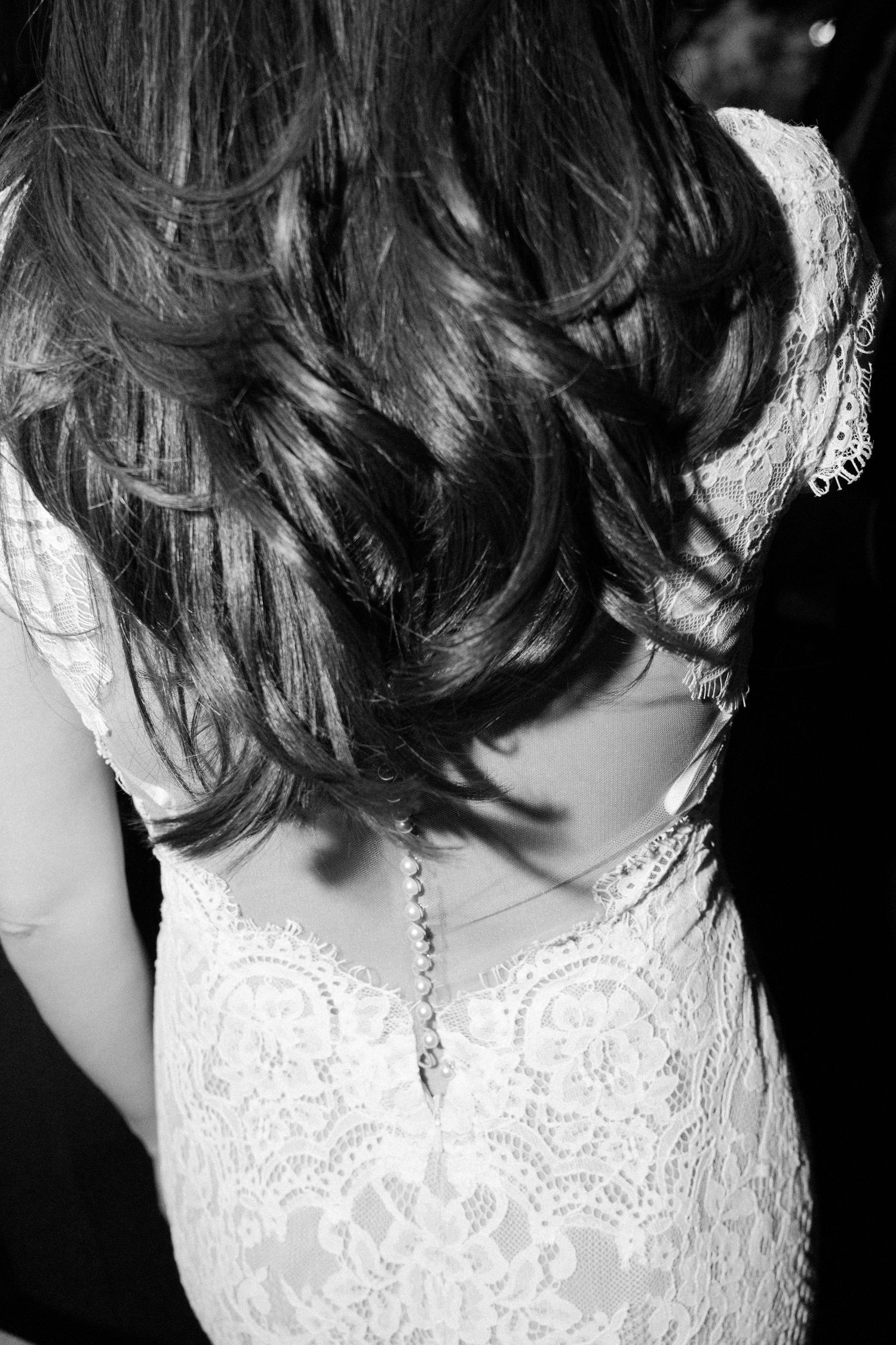 Detail shots of lace wedding dress back with button closures in black and white.