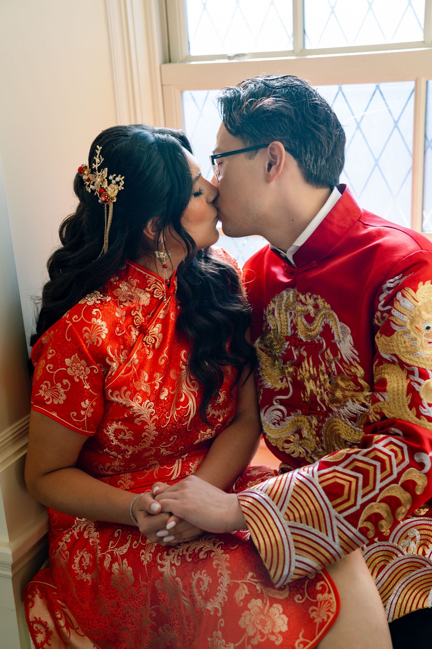Intimate moments captured in traditional Chinese wedding attire featuring red qipao with gold embroidery.